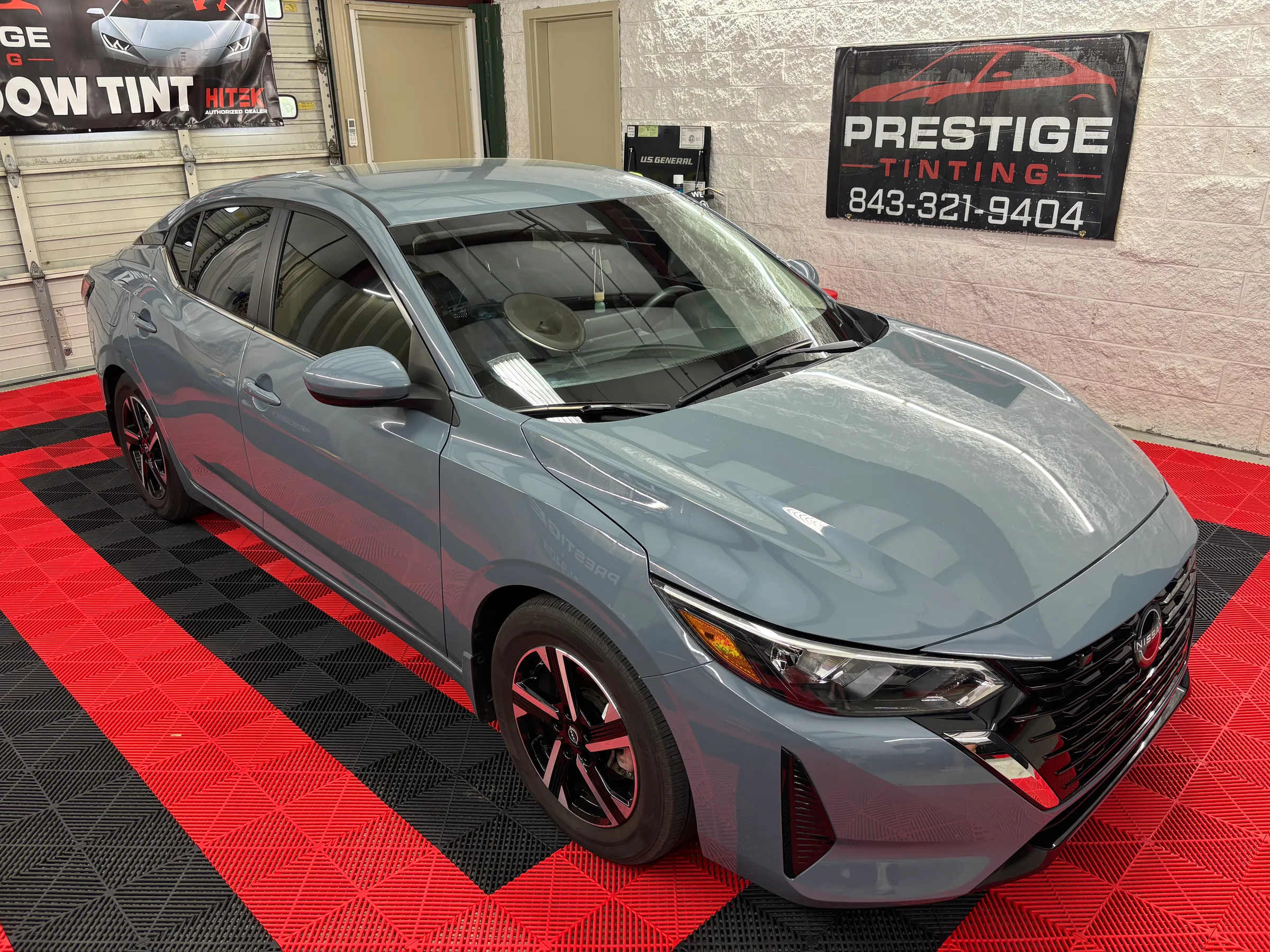 A gray Ford sedan with window tinting displayed in the showroom of Prestige Tinting in Conway, SC, featuring tinted windows and red alloy wheels.