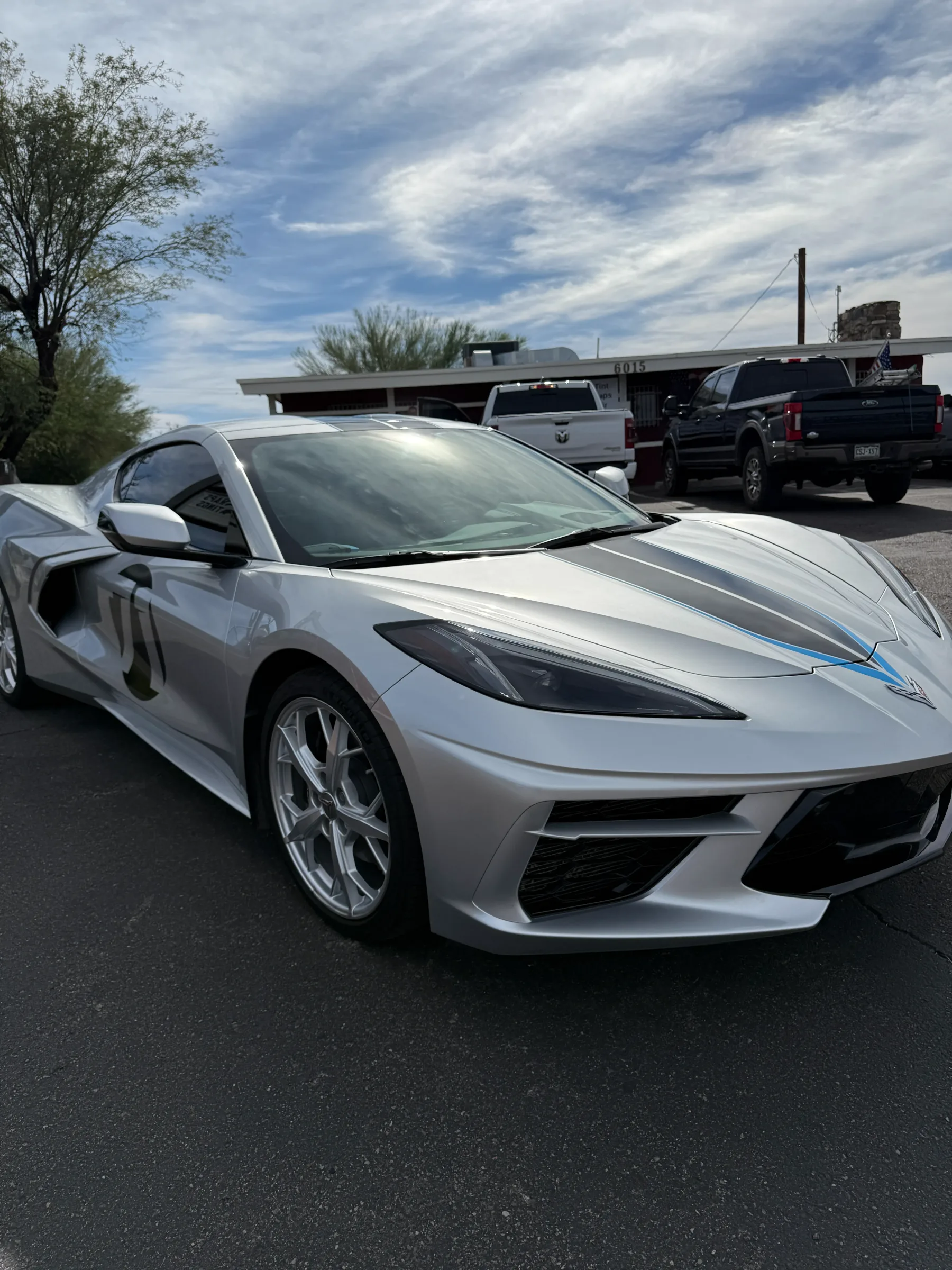 A white Chevrolet Corvette with window tint applied, parked at a service facility in Cave Creek, Arizona.