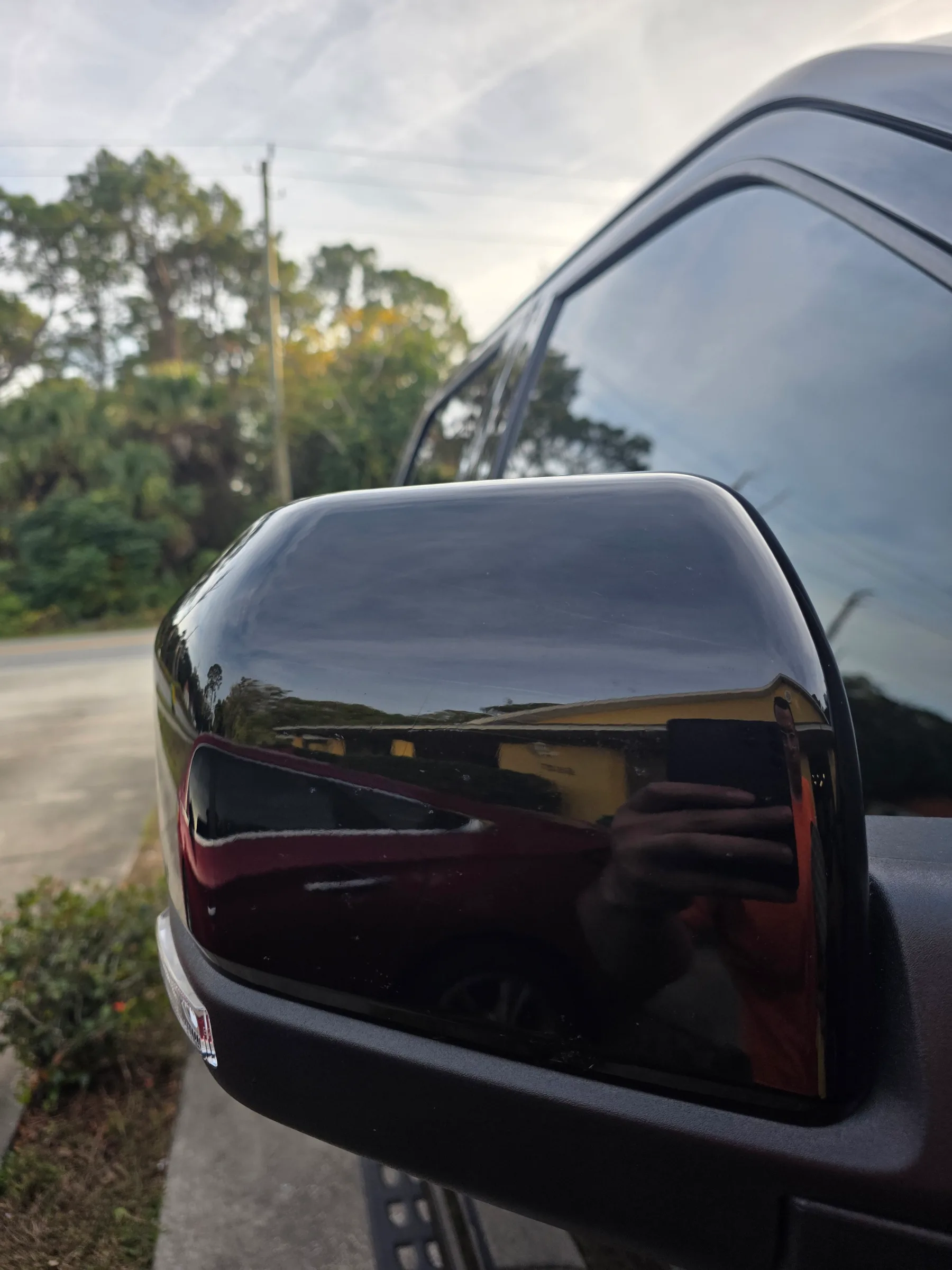 Close-up of a dark-tinted vehicle mirror and window showing the reflective results of window tinting on an SUV.
