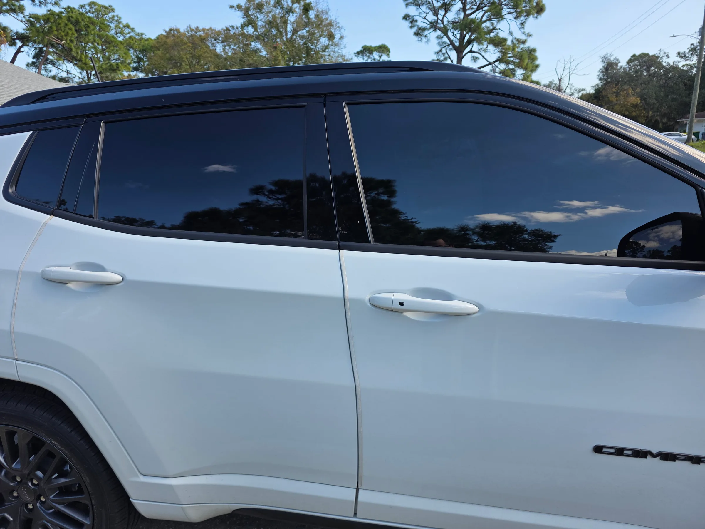 White GMC SUV with dark window tint applied to all side windows, photographed outdoors with trees in the background.