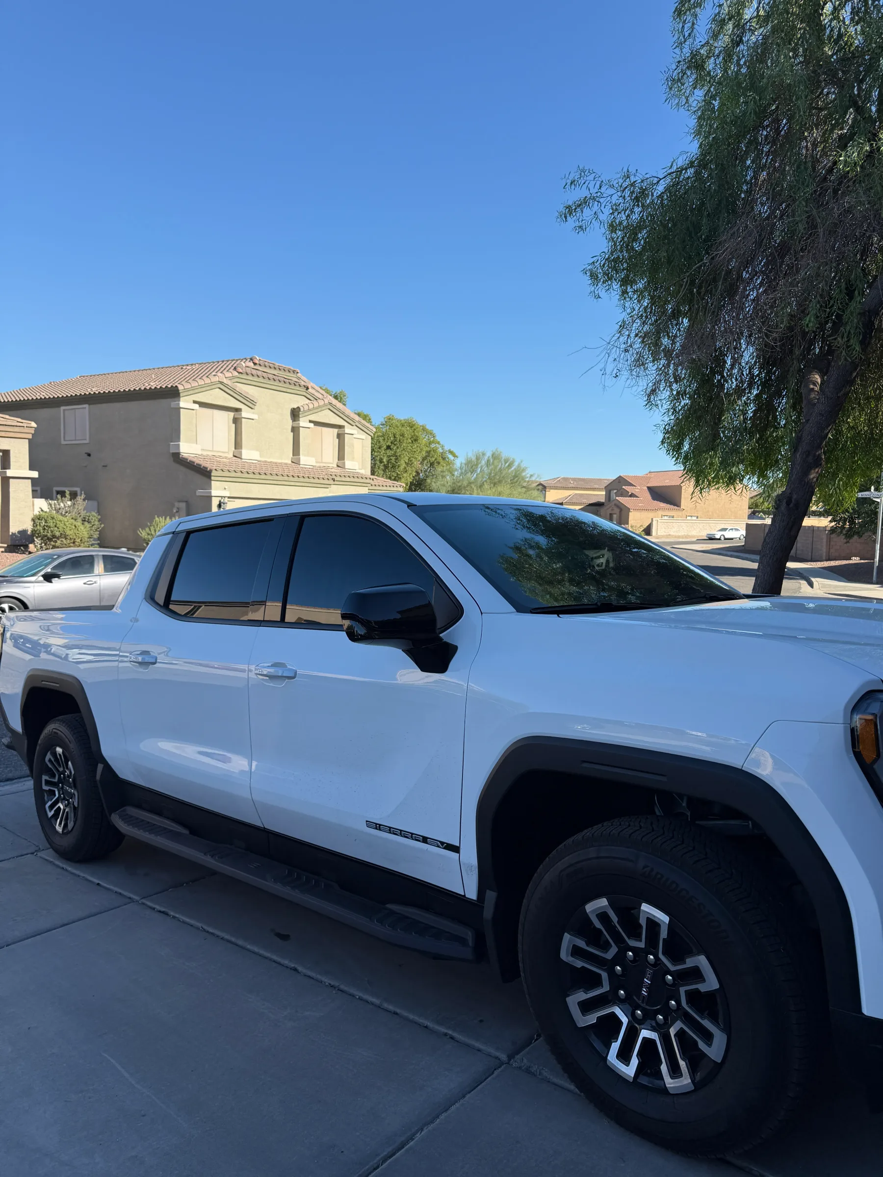 White GMC Sierra pickup truck with dark window tint applied to all windows, parked in a residential driveway in Cave Creek, Arizona.