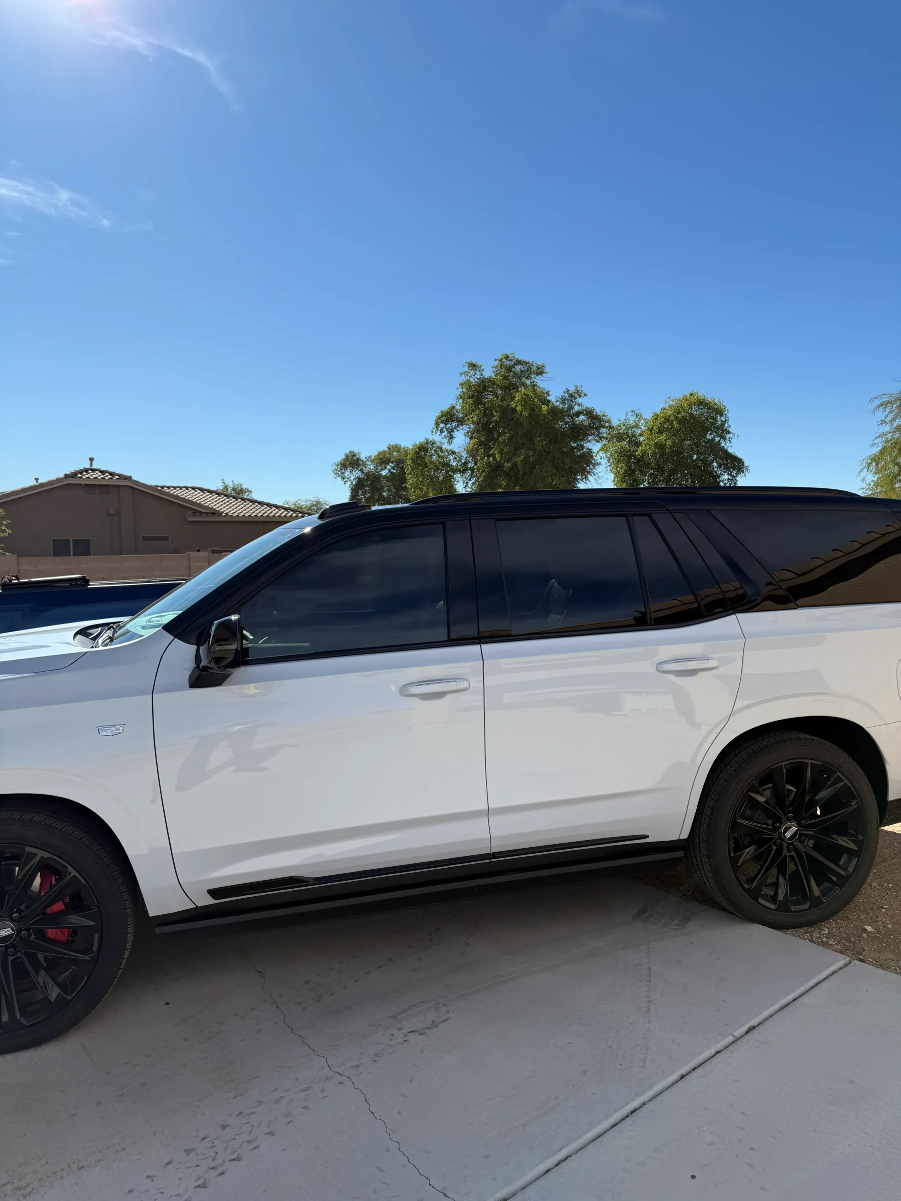 A white SUV with dark window tint applied to its rear and side windows, parked in a driveway in Cave Creek, Arizona.