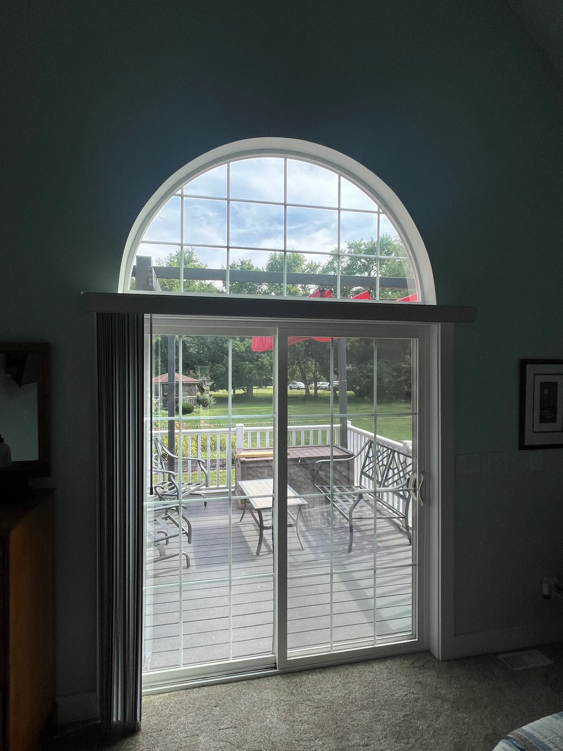 Interior view of large sliding glass doors and arched window with residential window tint applied, showing outdoor deck and landscape.