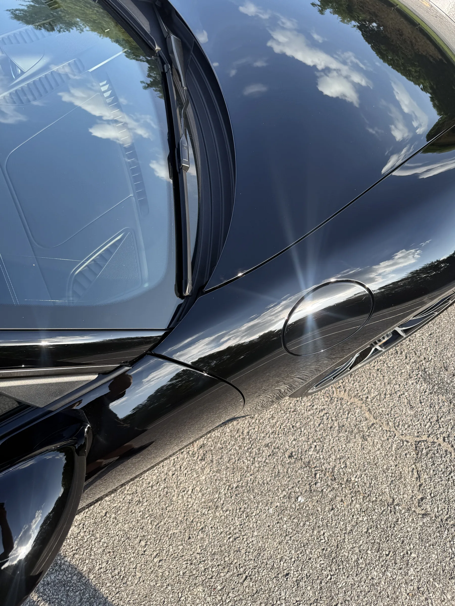 Close-up of a black vehicle's door edge and rocker panel showing protective film application along the lower body trim.