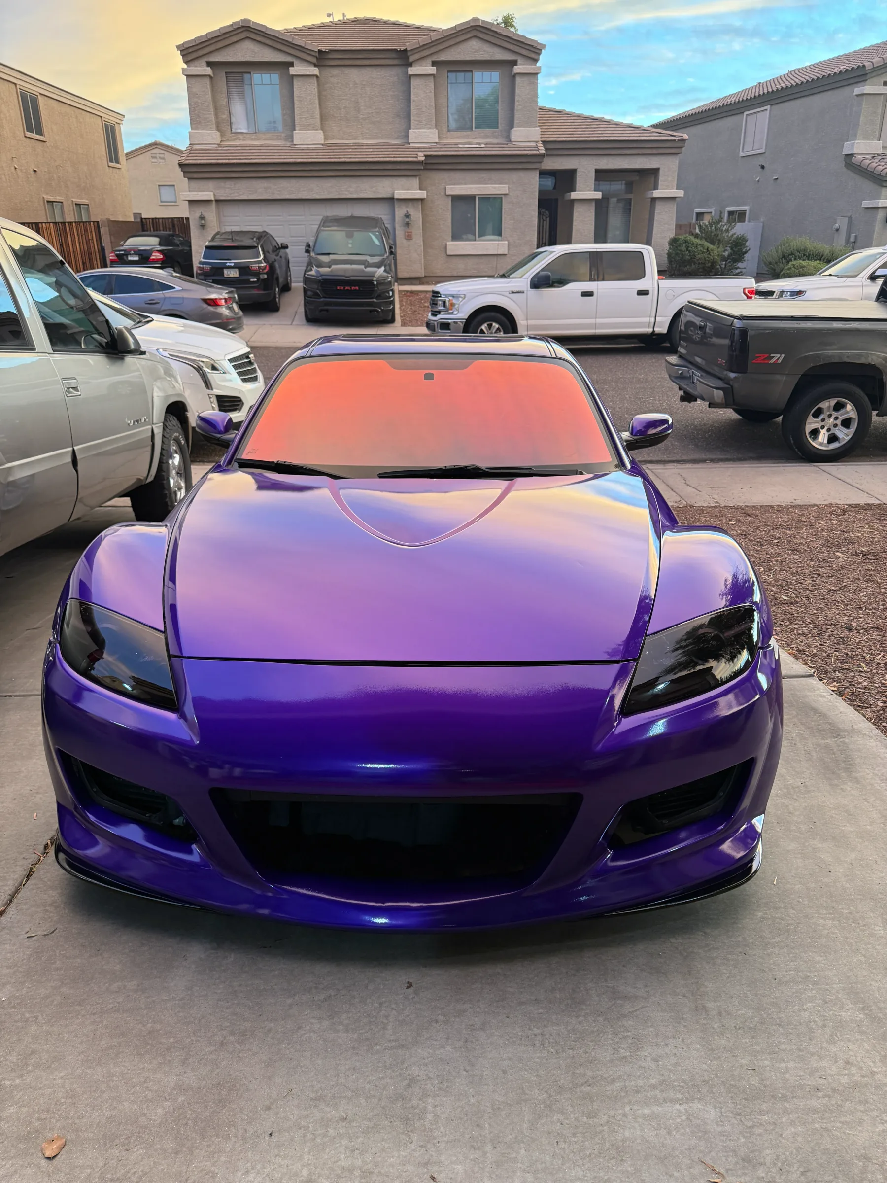 A purple sports car with a red-orange tinted windshield parked in a residential driveway in Cave Creek, Arizona.