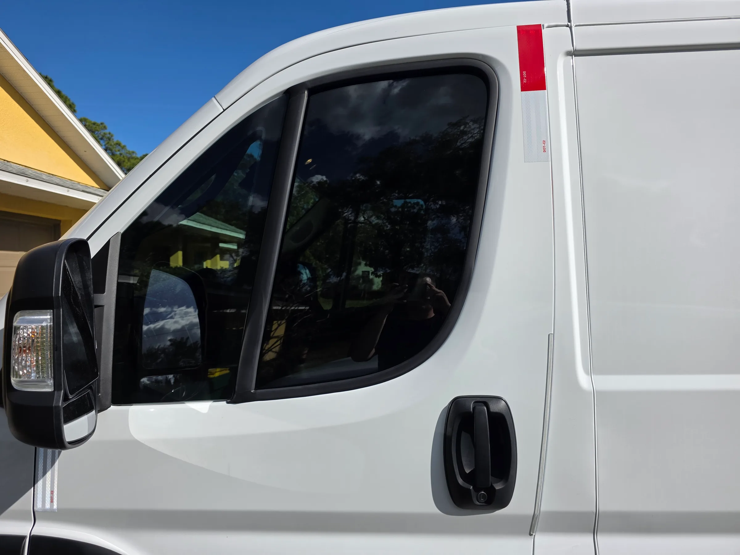 White commercial van with dark window tint applied to the cab windows, parked in bright sunlight.