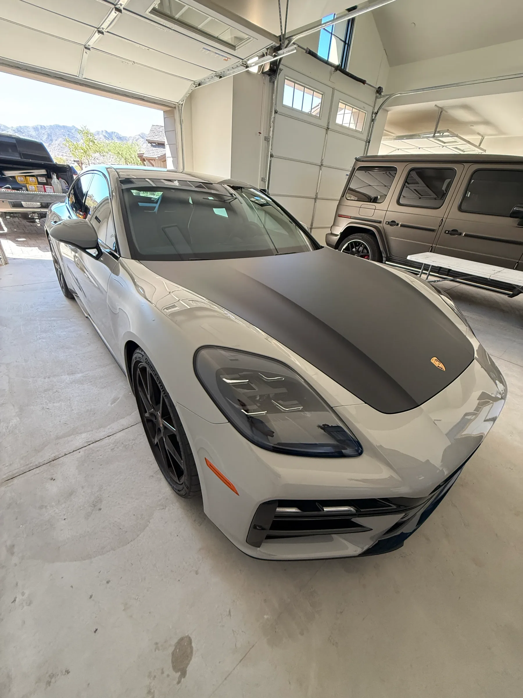 White Porsche sports car with tinted windows parked in a garage bay.