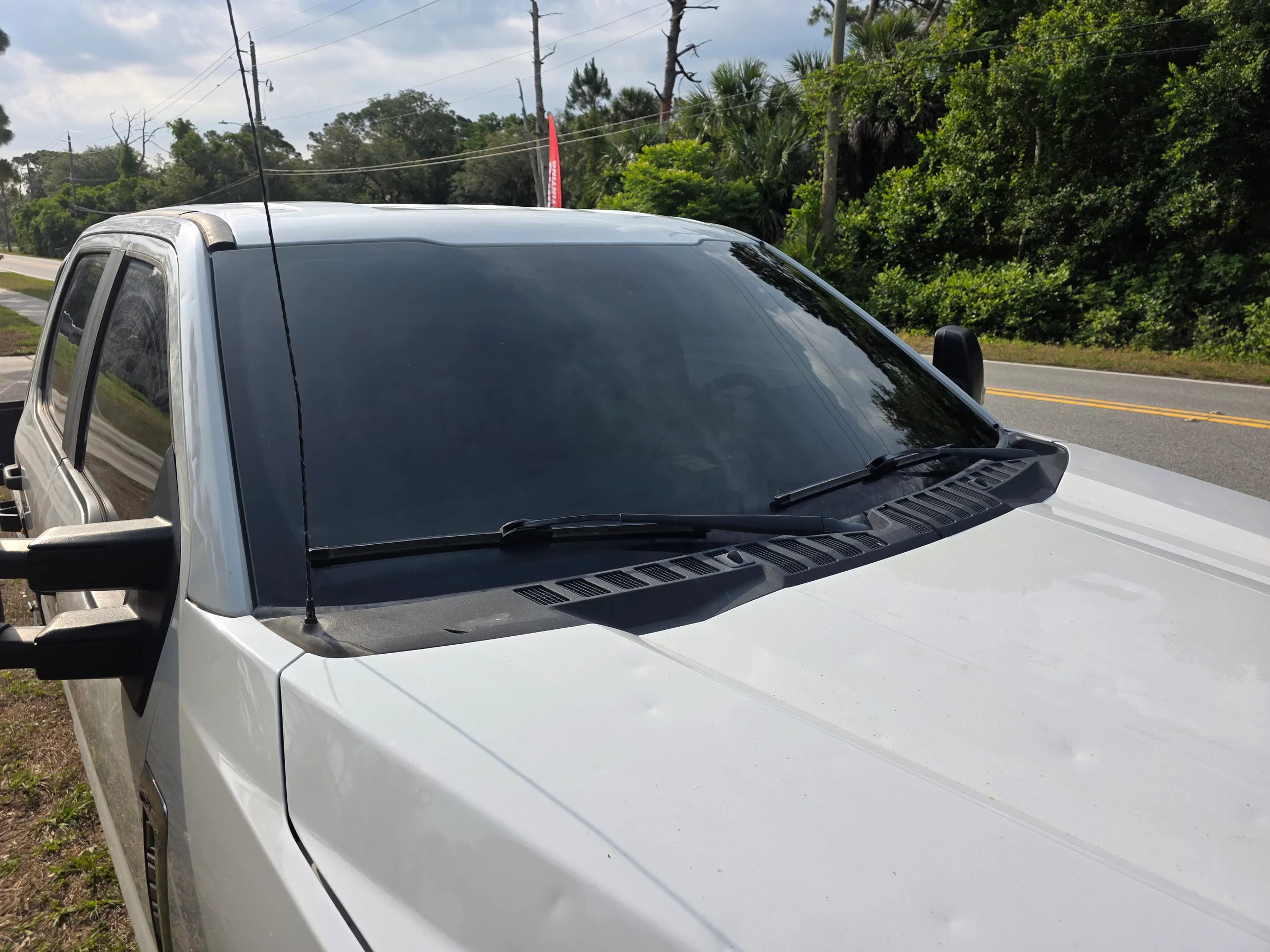 White pickup truck with dark window tint applied to the rear cab windows, parked on a residential roadside.