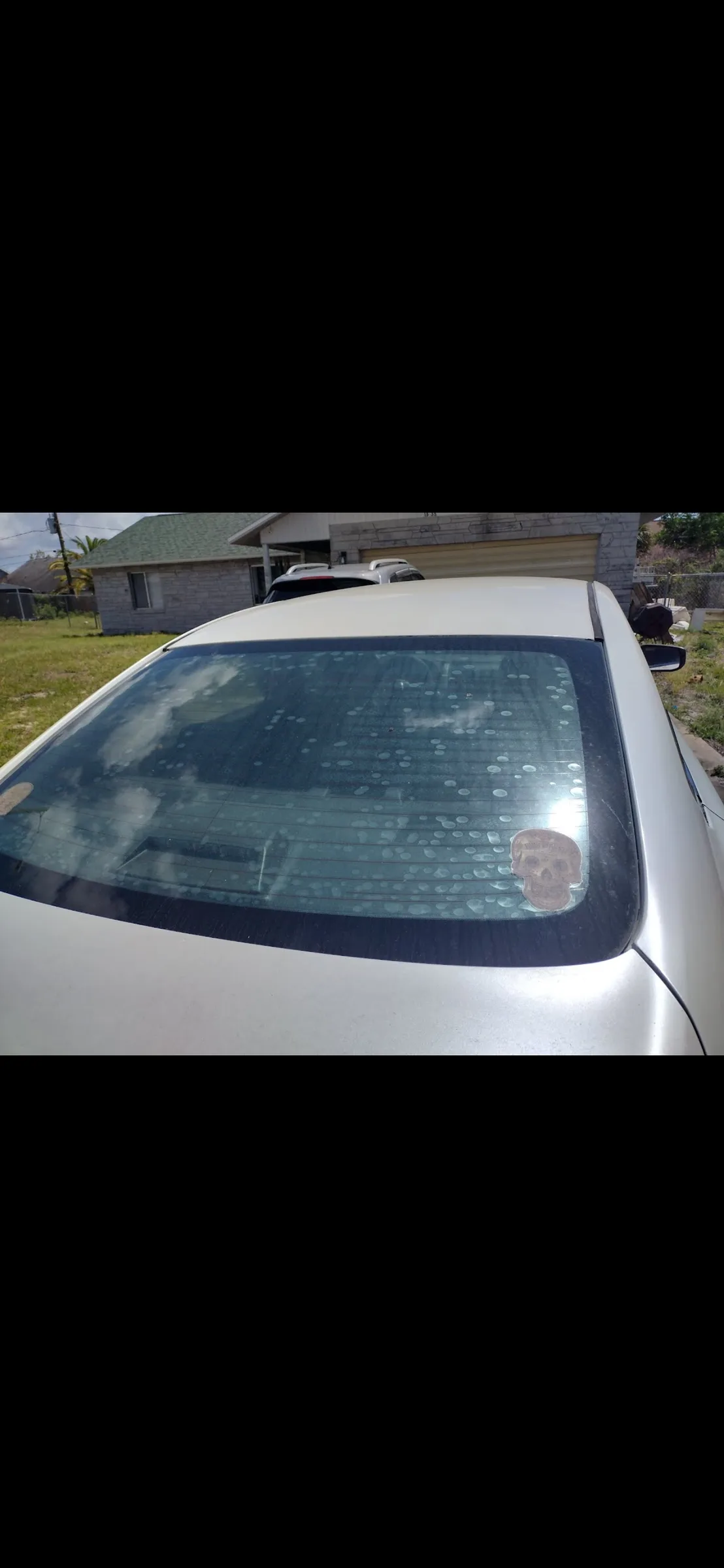 White vehicle parked in a residential driveway with tinted rear window and sunroof.