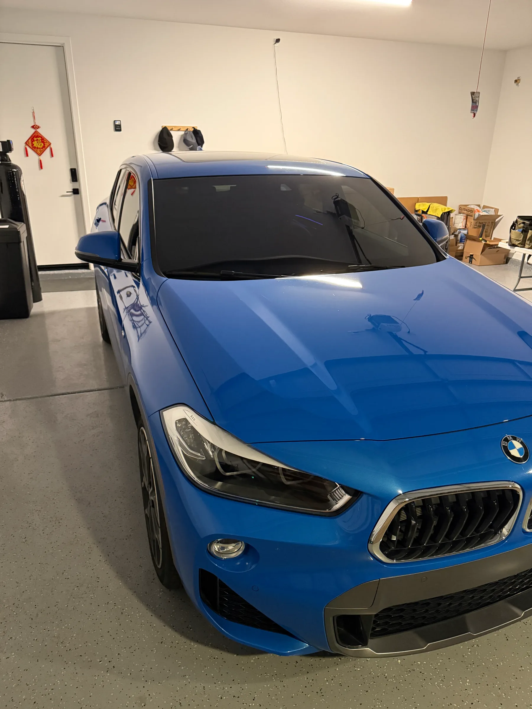 A blue BMW with tinted windows parked indoors at a tinting shop in Cave Creek.