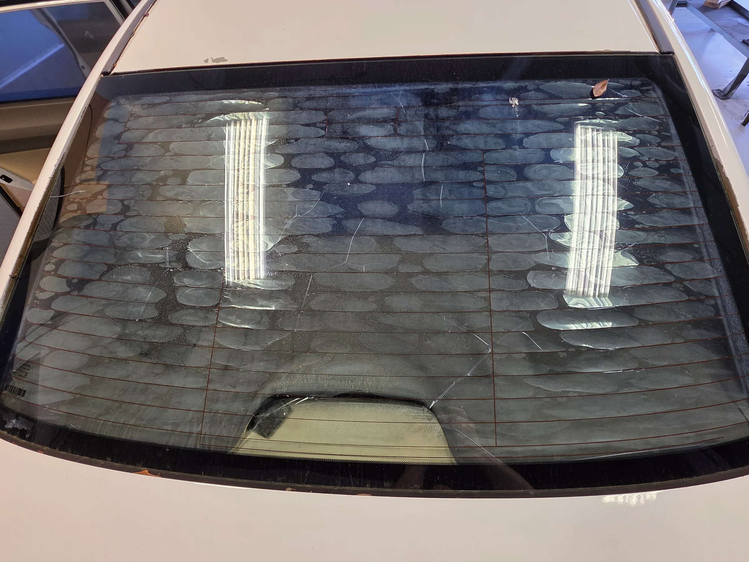 A vehicle's rear window with a dark window tint film applied, showing two reflective sun shade strips positioned vertically on the glass.