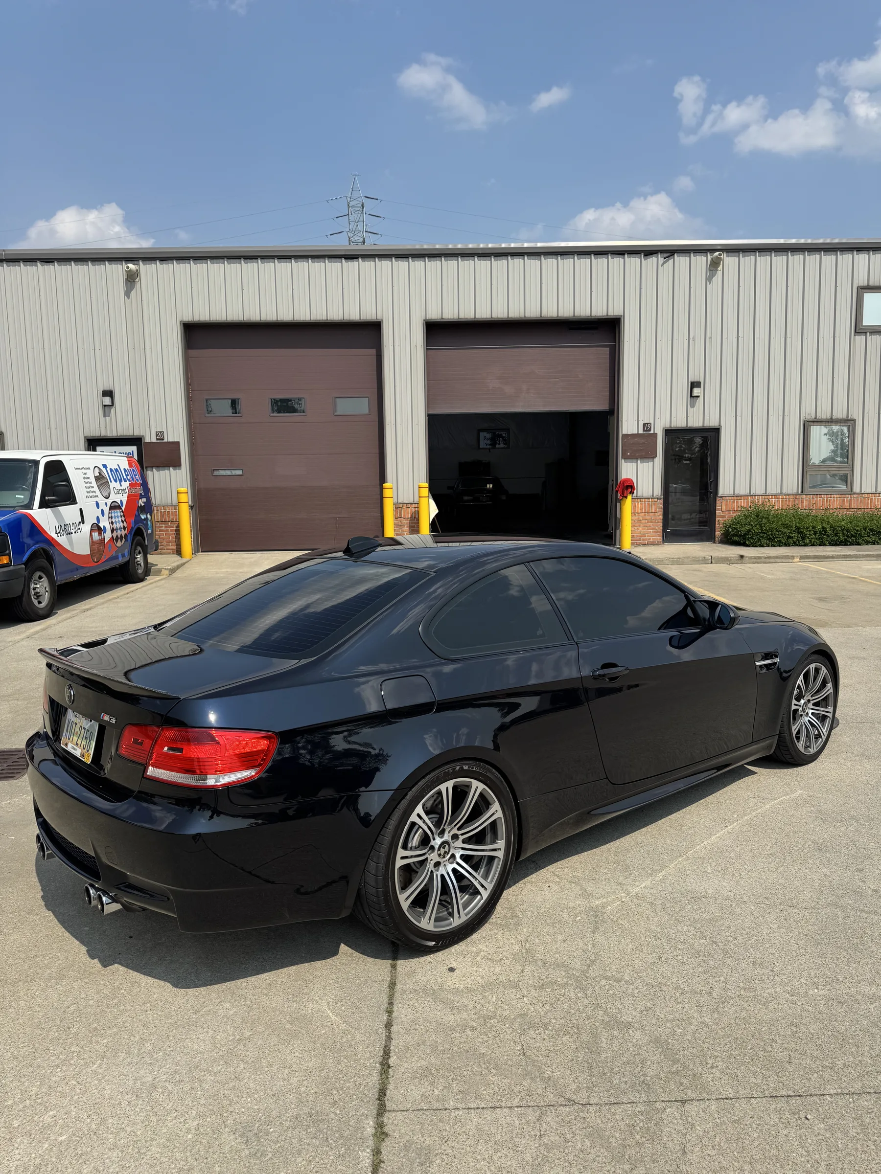 A black BMW M3 coupe parked outside a commercial garage facility in Berea, Ohio.