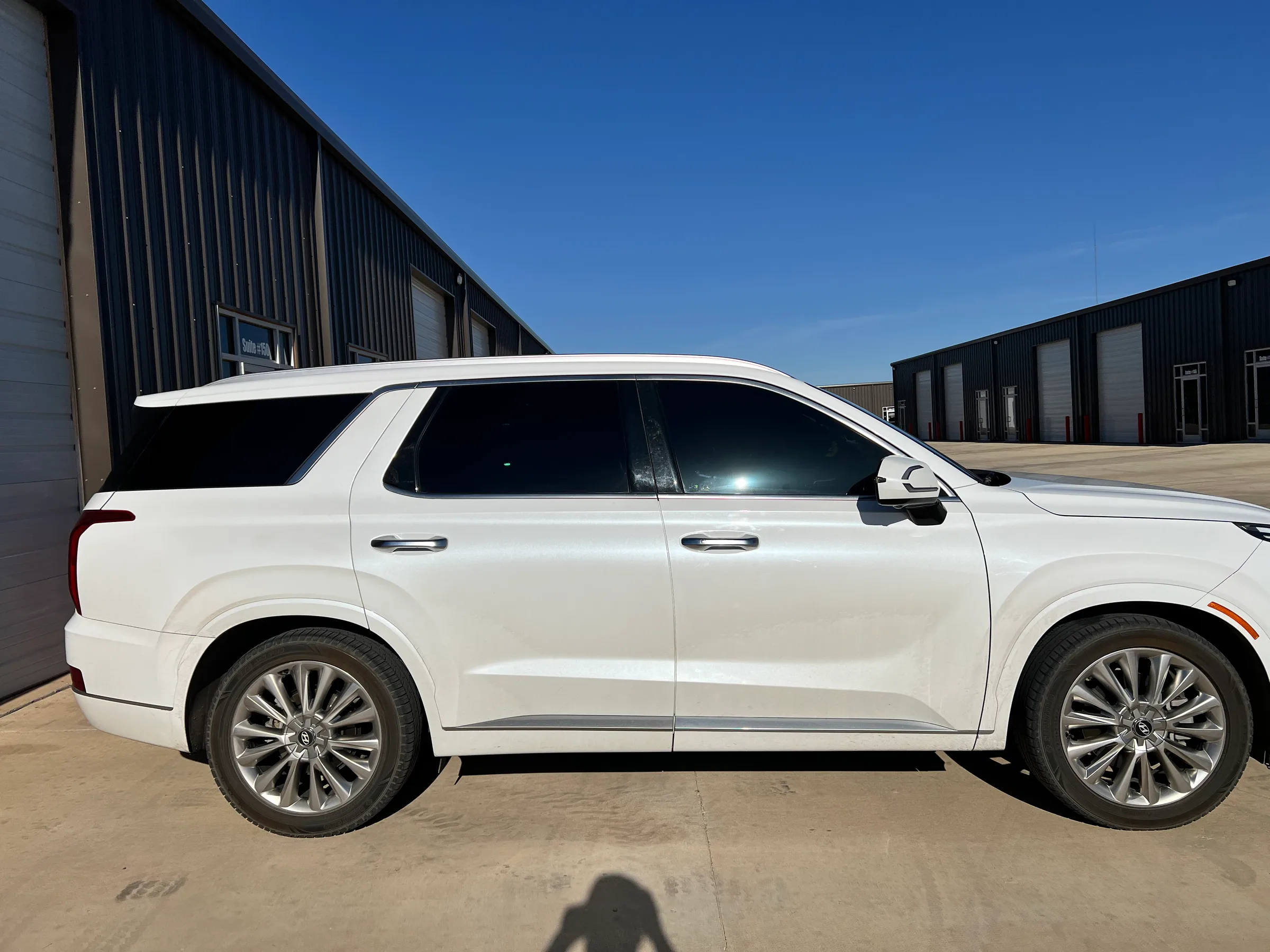 White Hyundai Palisade with dark window tint applied to the rear and side windows, parked at a commercial facility in Lubbock.