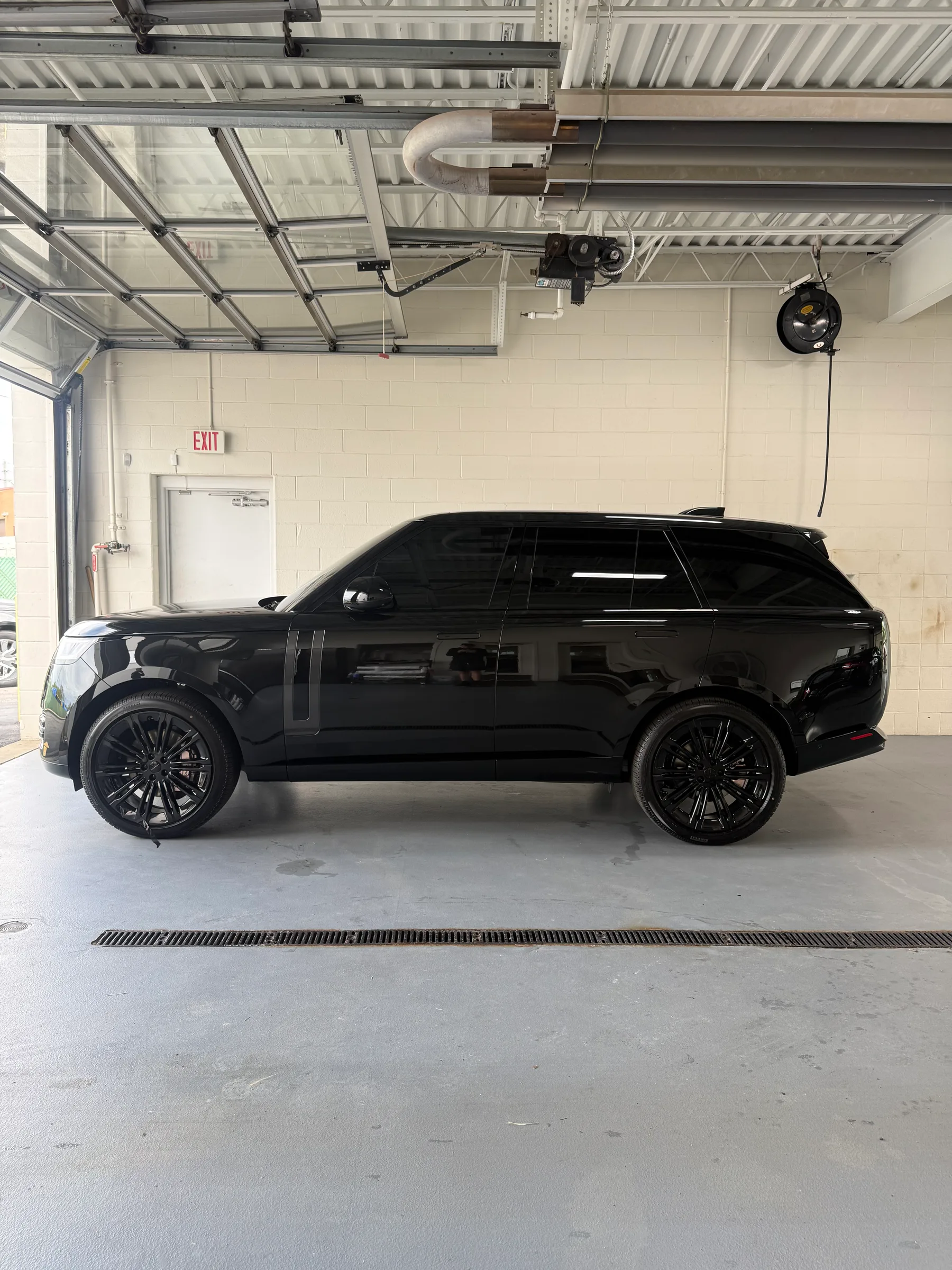 A black Range Rover Sport with dark tinted windows parked inside a professional auto service bay in Berea.