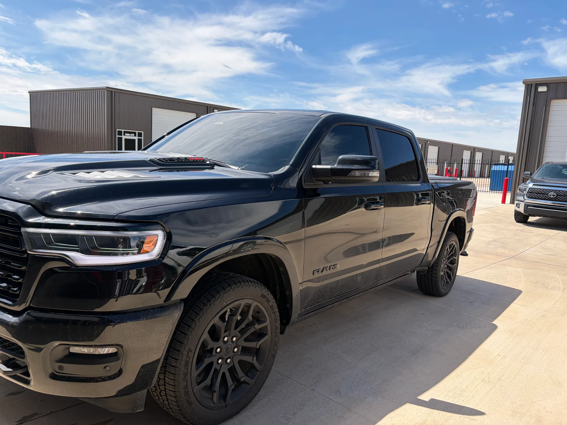 Front view of a black RAM 1500 truck with dark window tint applied, parked at a facility in Lubbock.