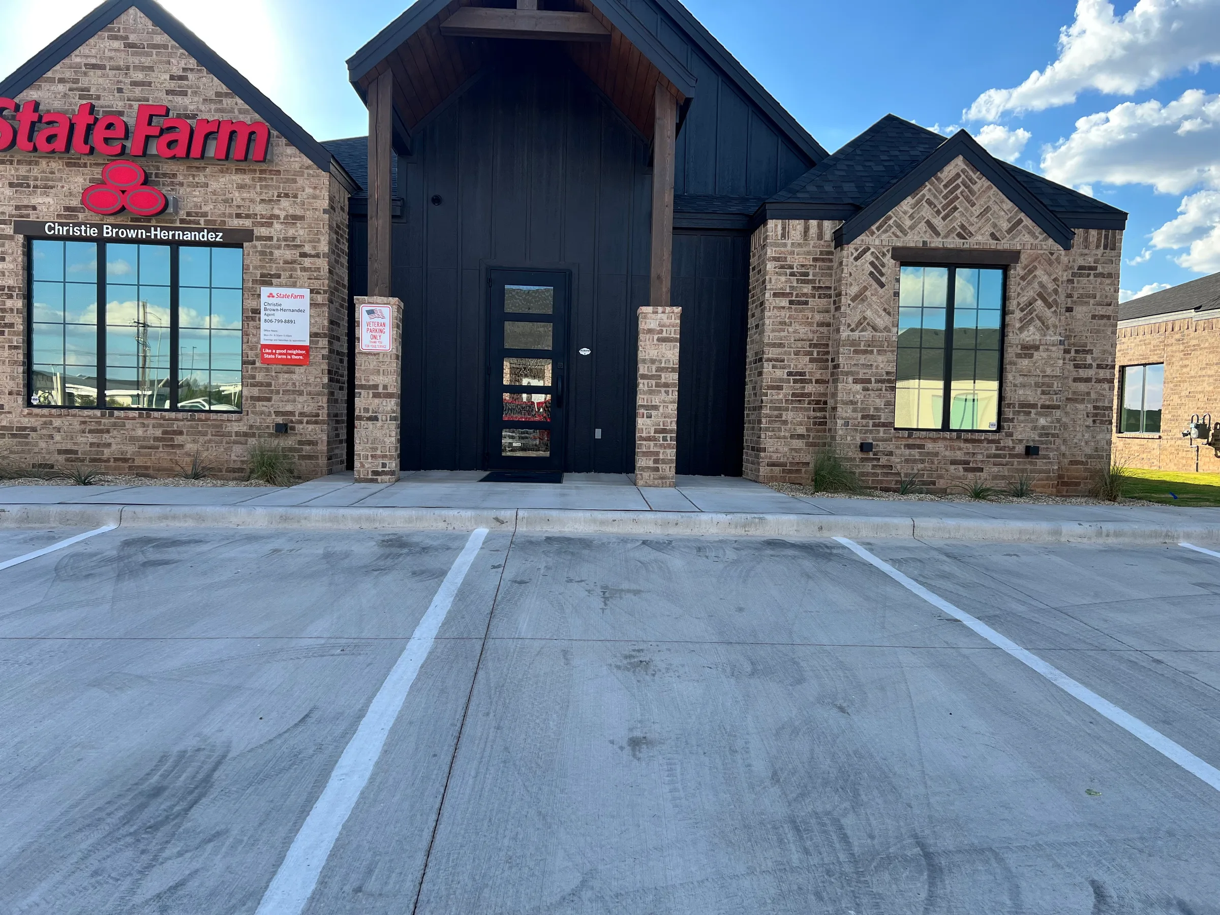 A State Farm office building in Lubbock with tinted windows on the brick storefront, showing the agent Christie Brown-Hernandez's name and signage.