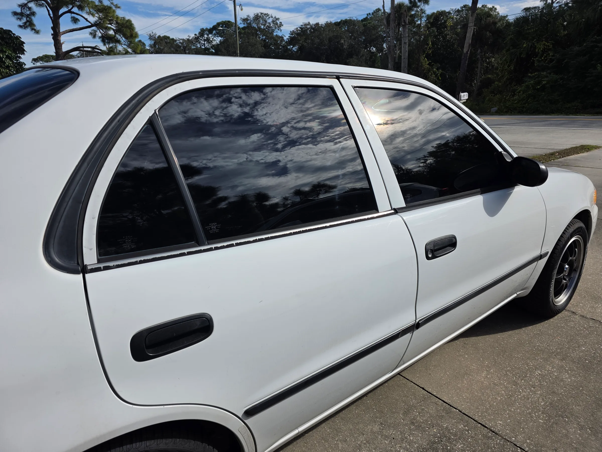 A white SUV or truck with dark window tint applied to the side windows, parked outdoors in Saint Croix Falls, Wisconsin.