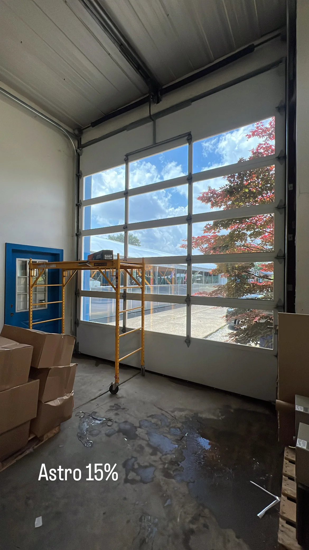 Interior view of a commercial glass door and window system displaying an Astro 15% window tint demonstration, showing the tint's effect on light transmission and outdoor visibility.
