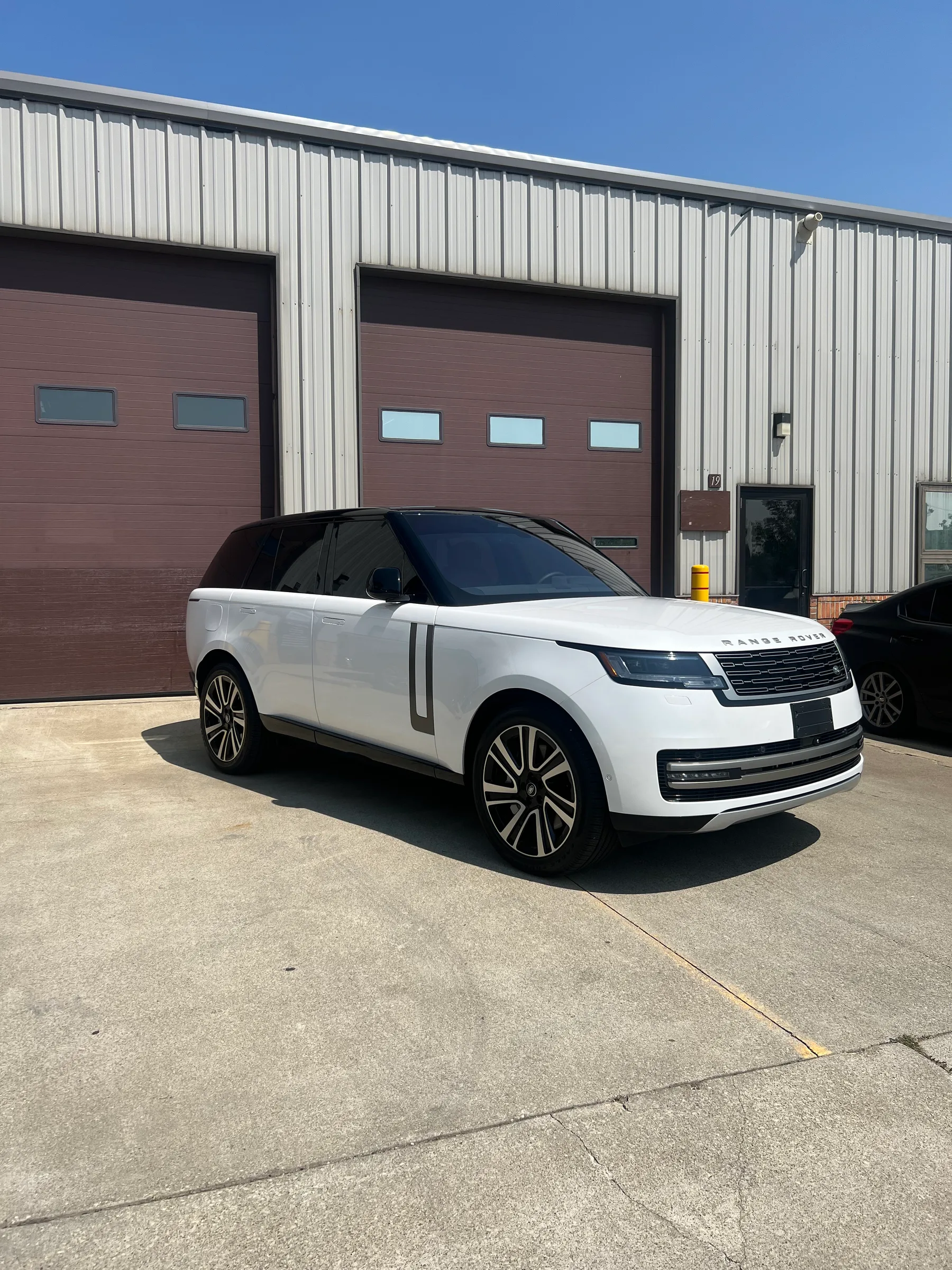 White Range Rover with black chrome delete accents parked in front of an automotive service facility in Berea.