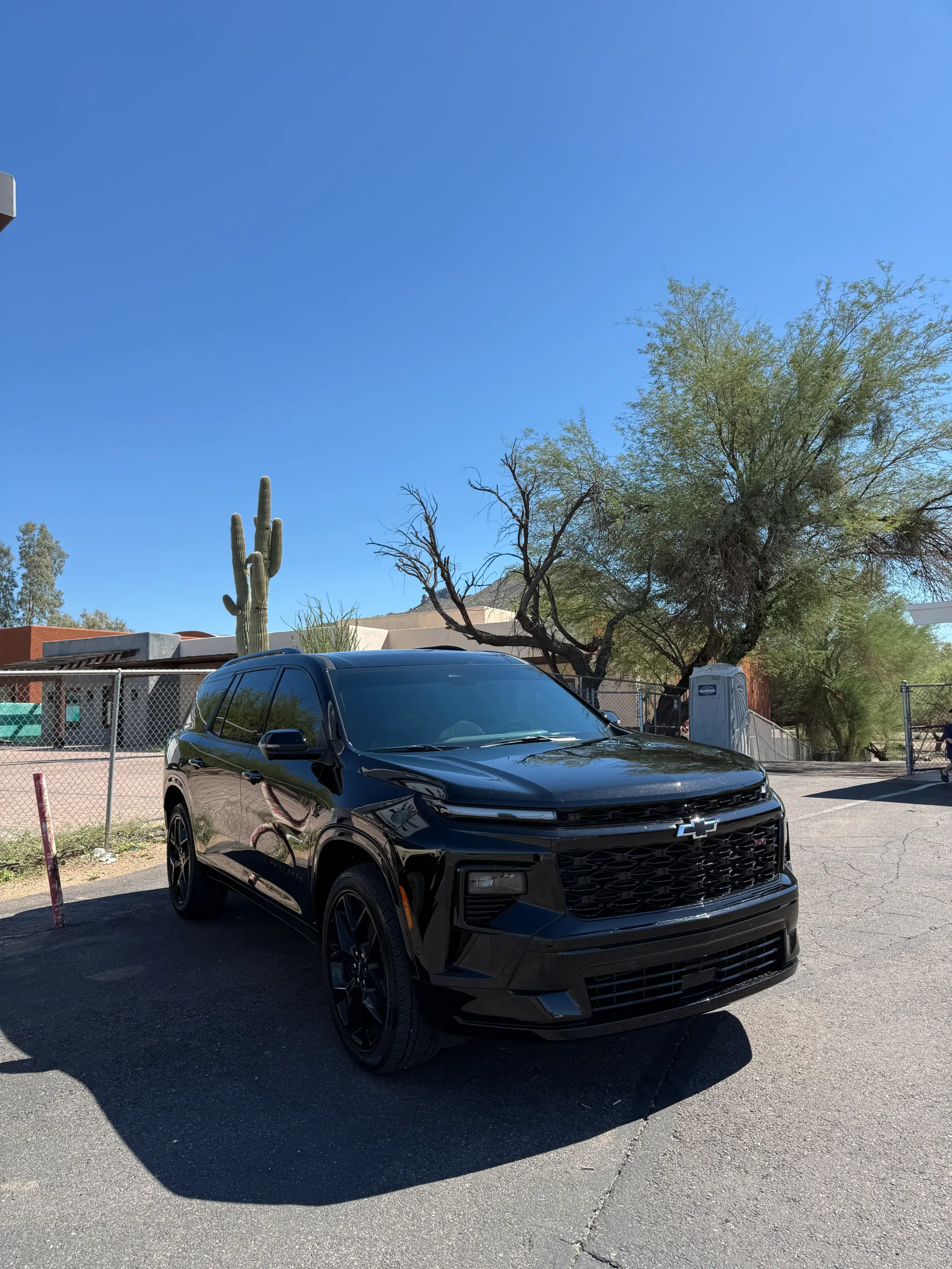 A black Chevrolet Equinox SUV with darkly tinted windows parked in a desert setting with saguaro cacti and desert vegetation visible in the background.
