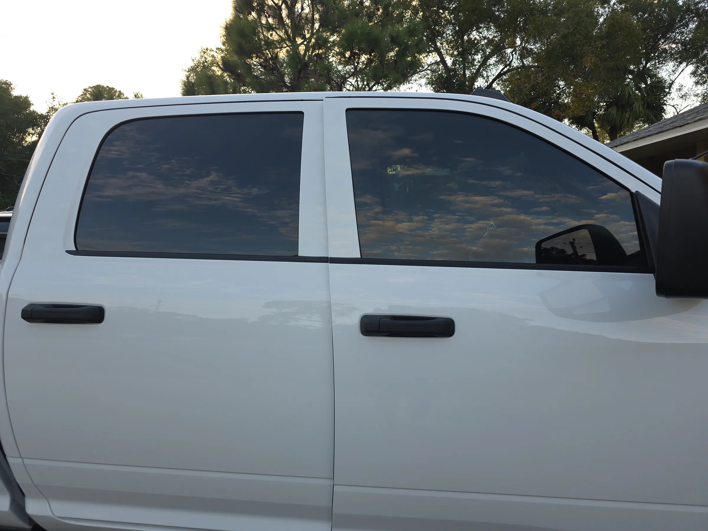 A white pickup truck with dark window tint applied to the rear passenger windows, photographed outdoors.