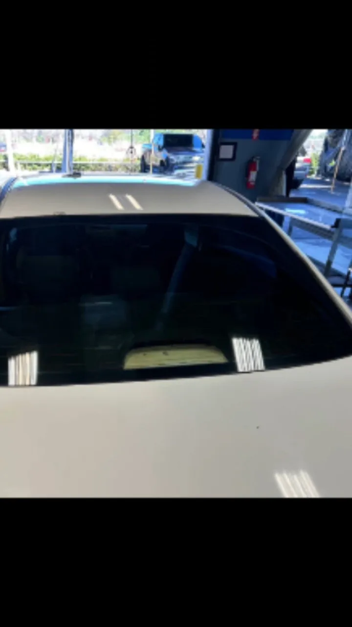 White pickup truck with dark window tint applied to the rear cabin glass, photographed in an indoor shop setting.