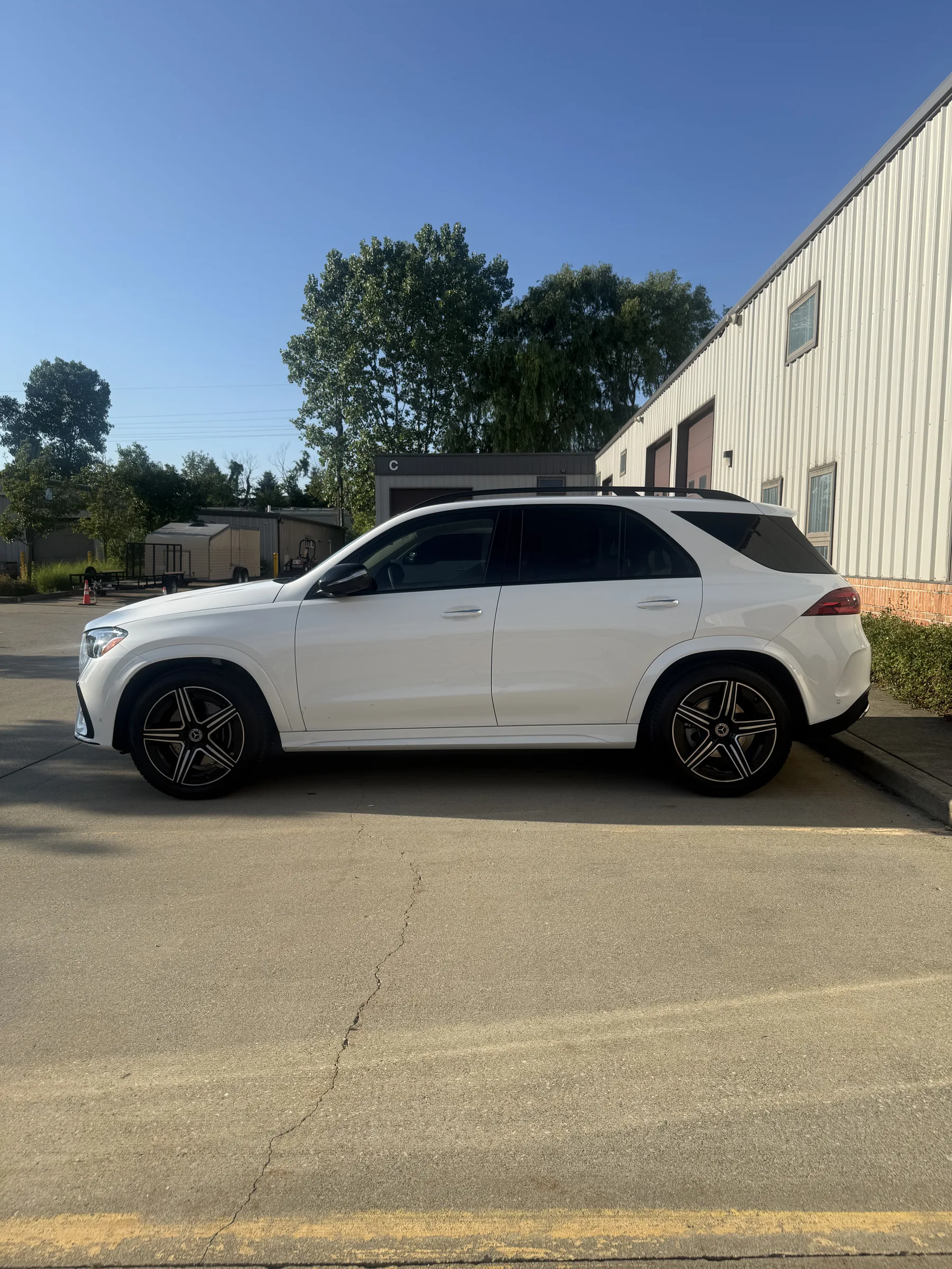 A white Mercedes-Benz GLE SUV with dark tinted windows parked in front of an industrial facility in Berea, Ohio.