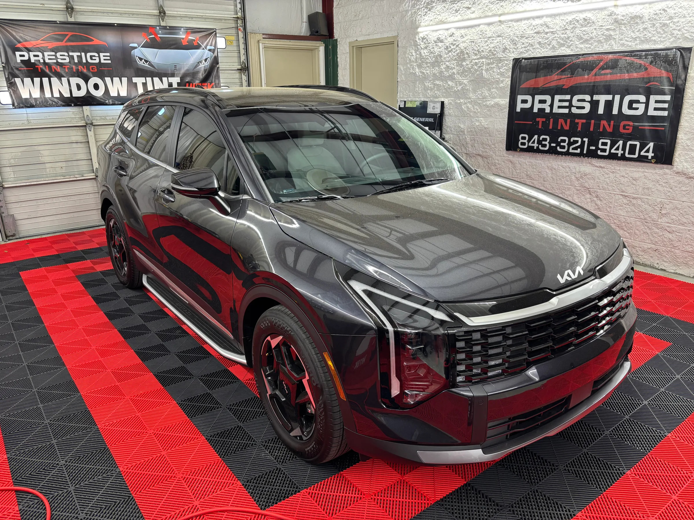 A silver and red Kia Sportage with window tint displayed in the Prestige Tinting showroom in Conway, SC.