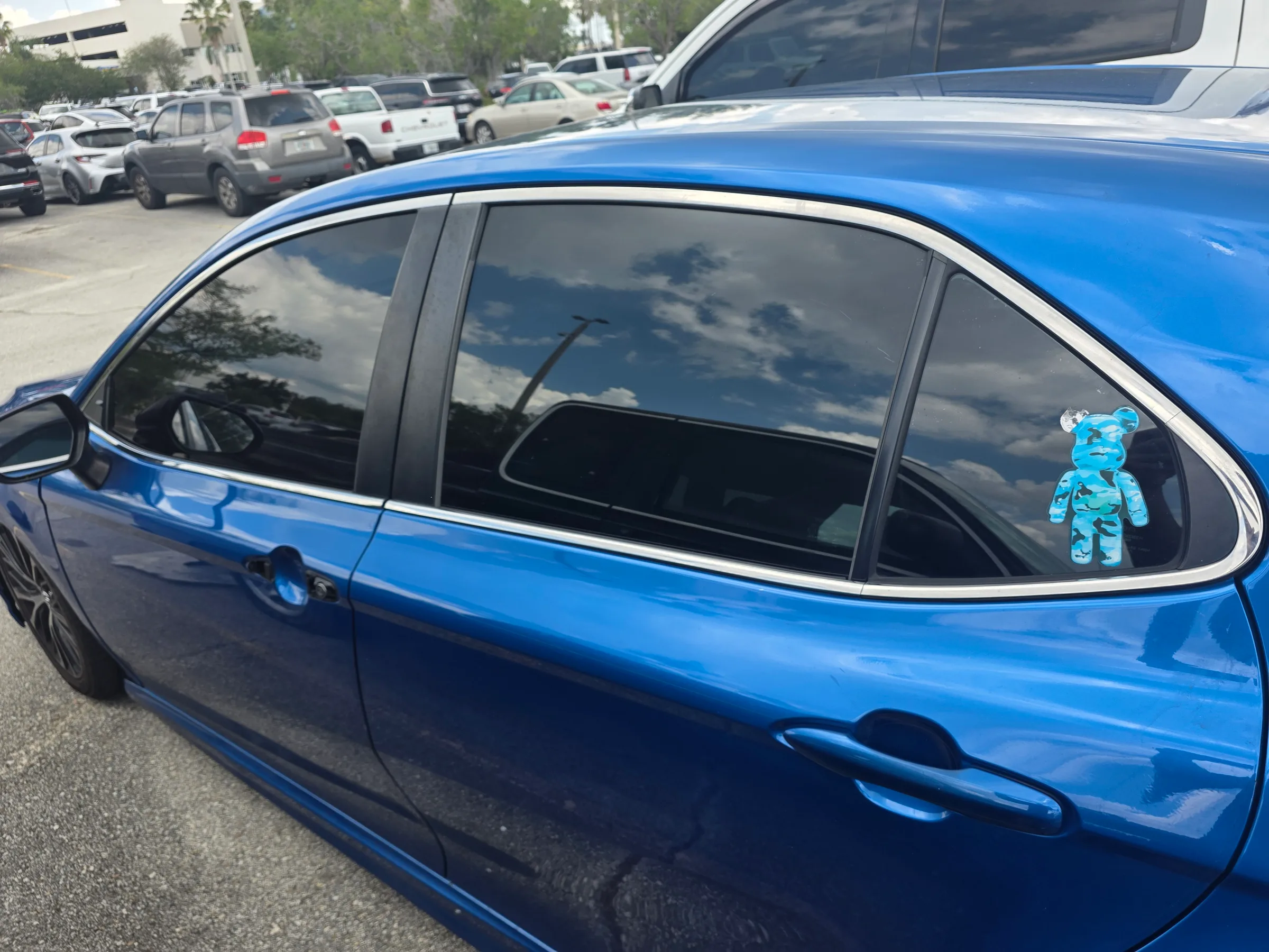 Bright blue sedan with dark tinted windows parked in a lot, showing professional window tint application.