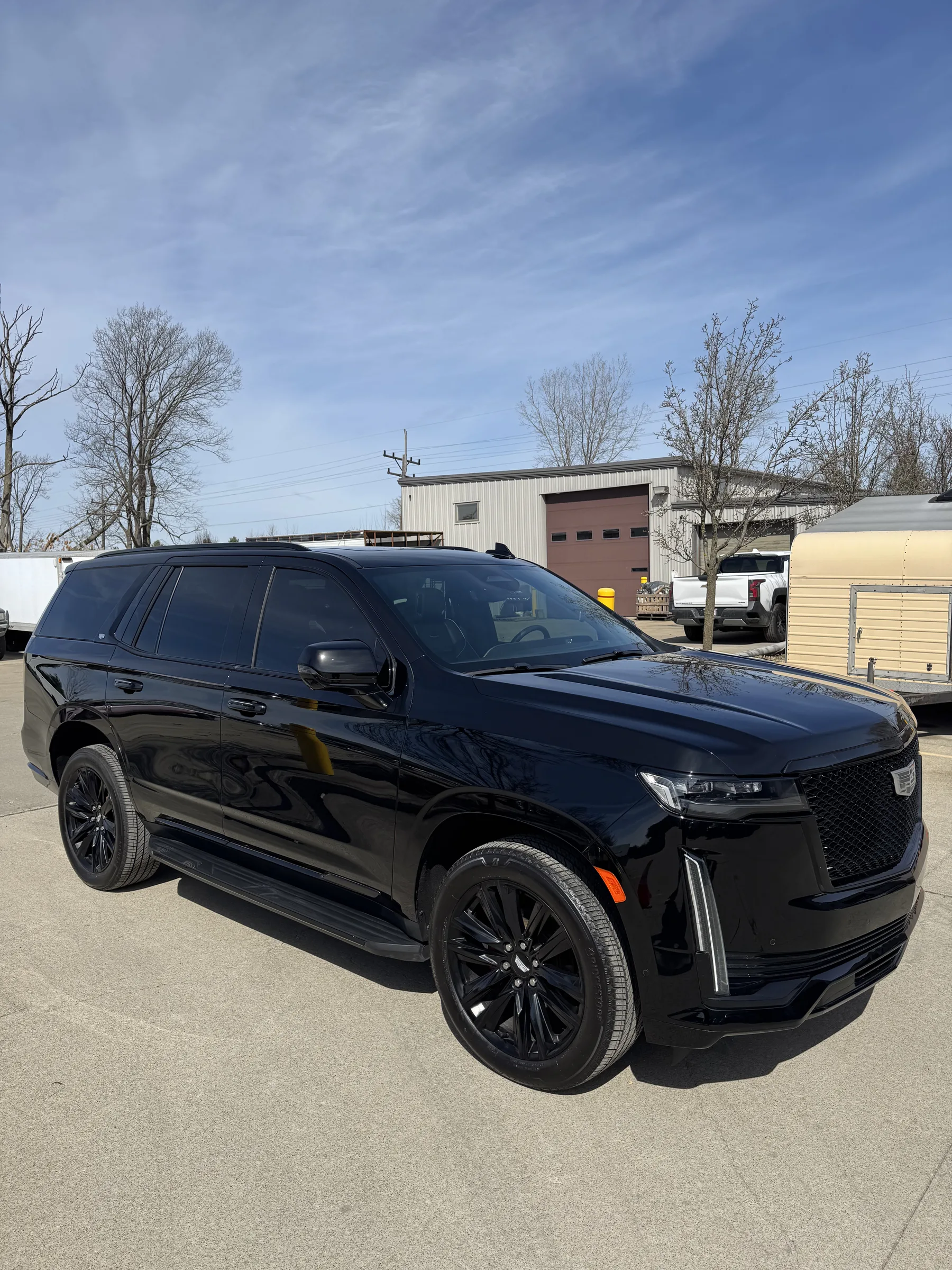 A black Cadillac Escalade SUV with darkly tinted windows parked at a commercial facility in Berea, Ohio.