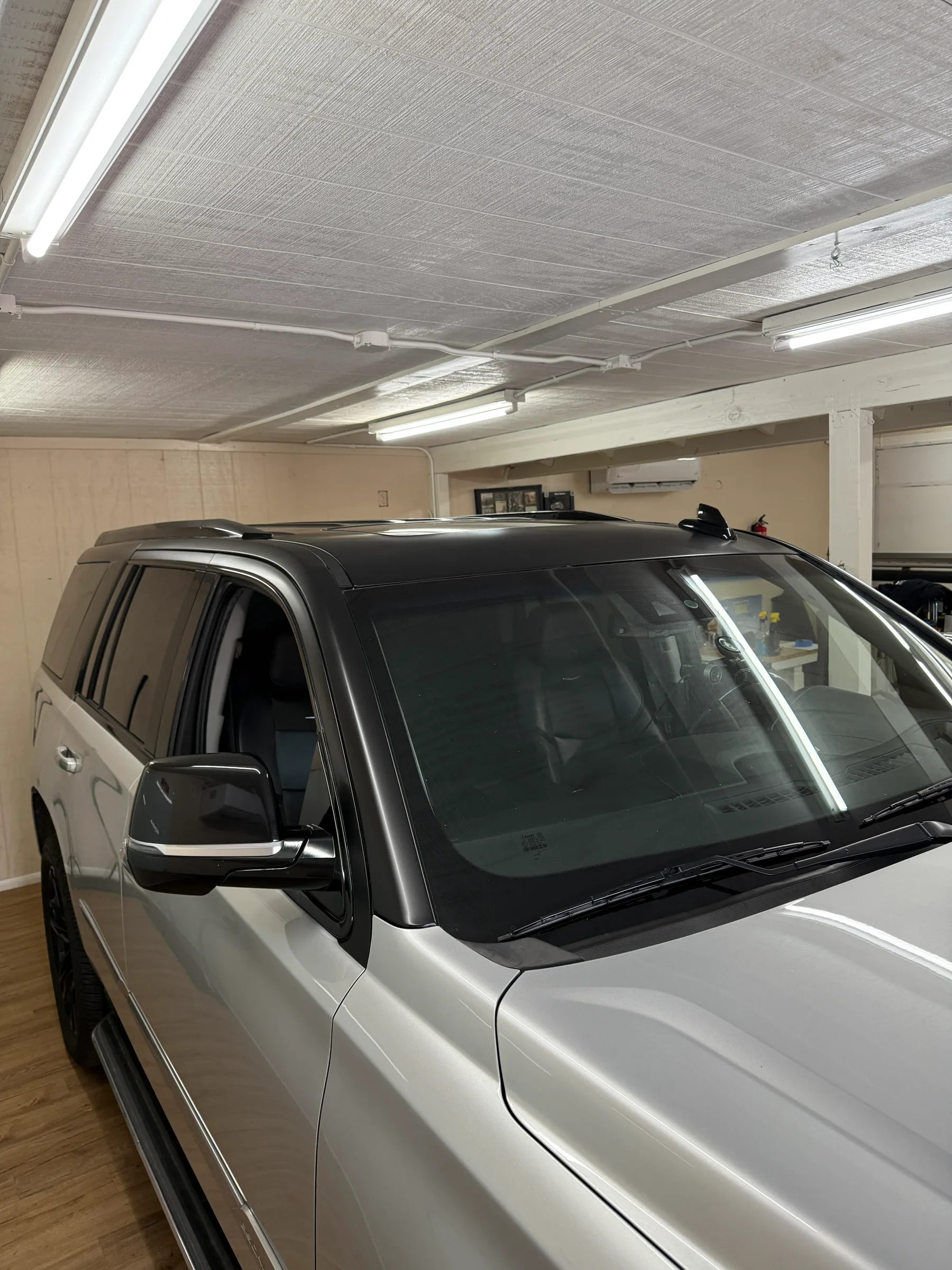 White SUV with dark window tint applied to the windows, parked in an indoor shop bay under bright fluorescent lighting.