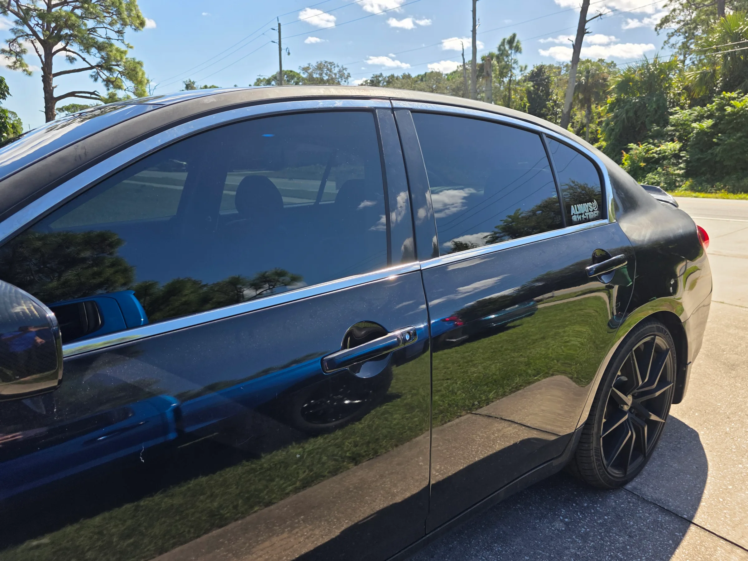A blue sedan parked outdoors with dark window tint applied to all windows, showing professional automotive tint work.