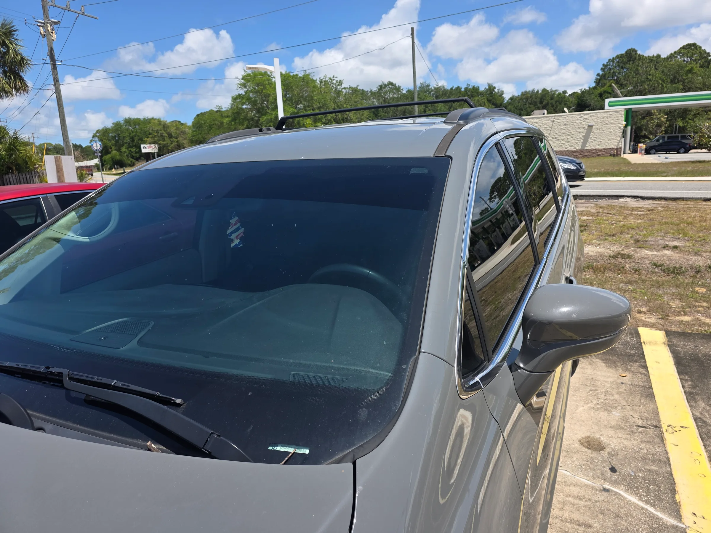 Silver pickup truck with dark window tint applied to the cab windows, parked in a service lot.