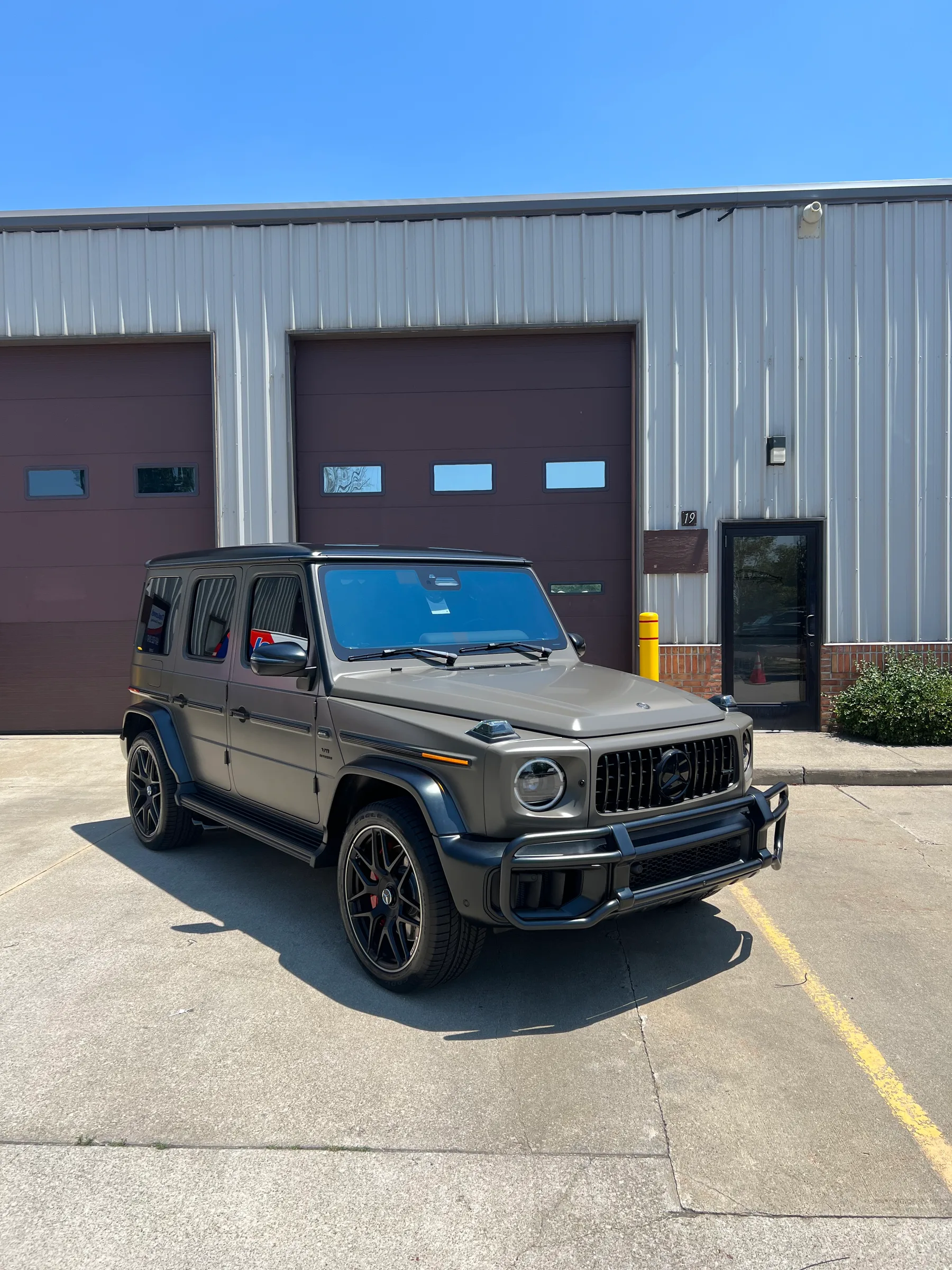 A gray Mercedes-AMG G-Class SUV with blue-tinted windows parked in front of a commercial garage in Berea.