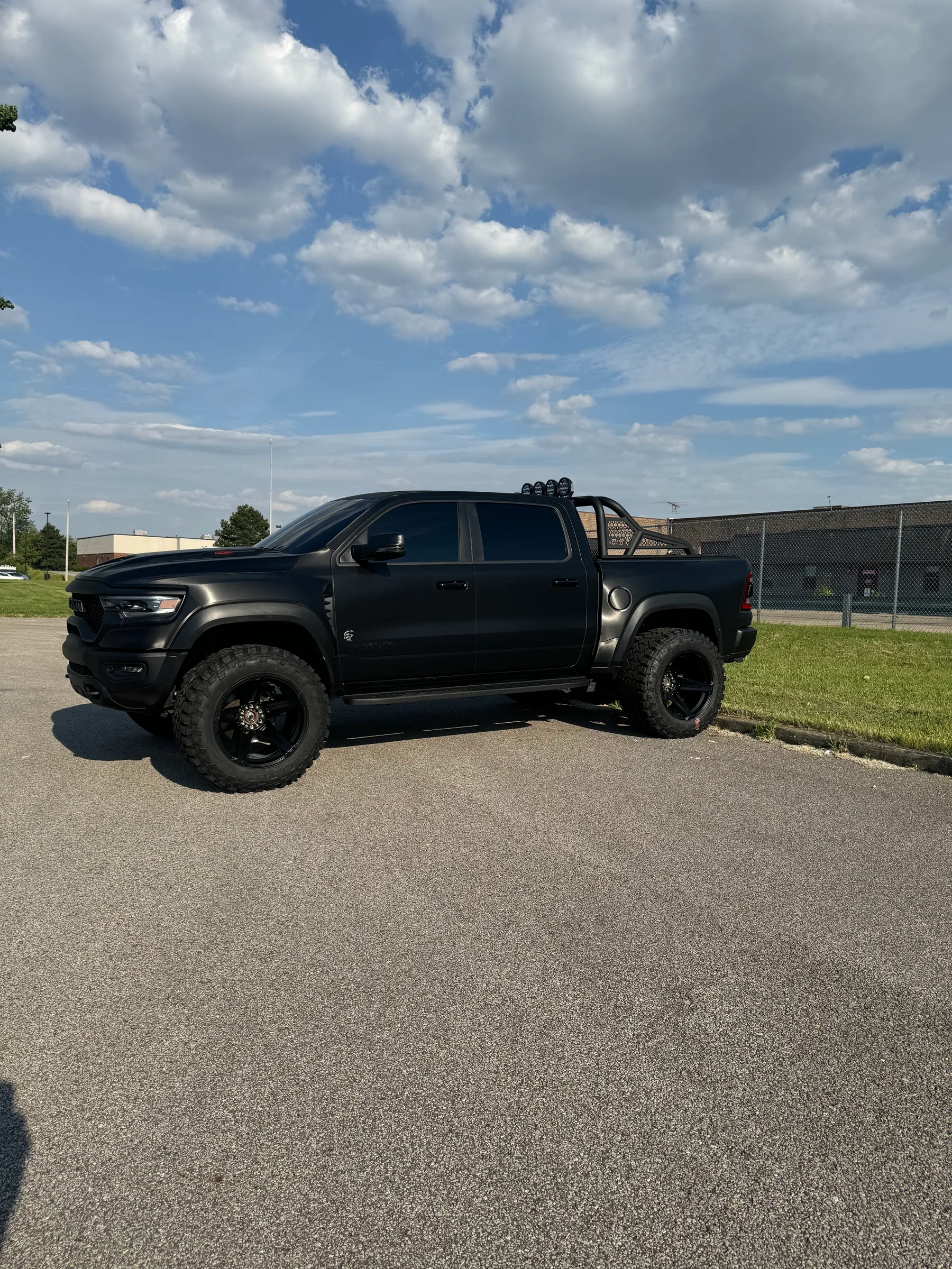 A black Ford Ranger pickup truck with tinted windows parked in a lot under a cloudy sky.