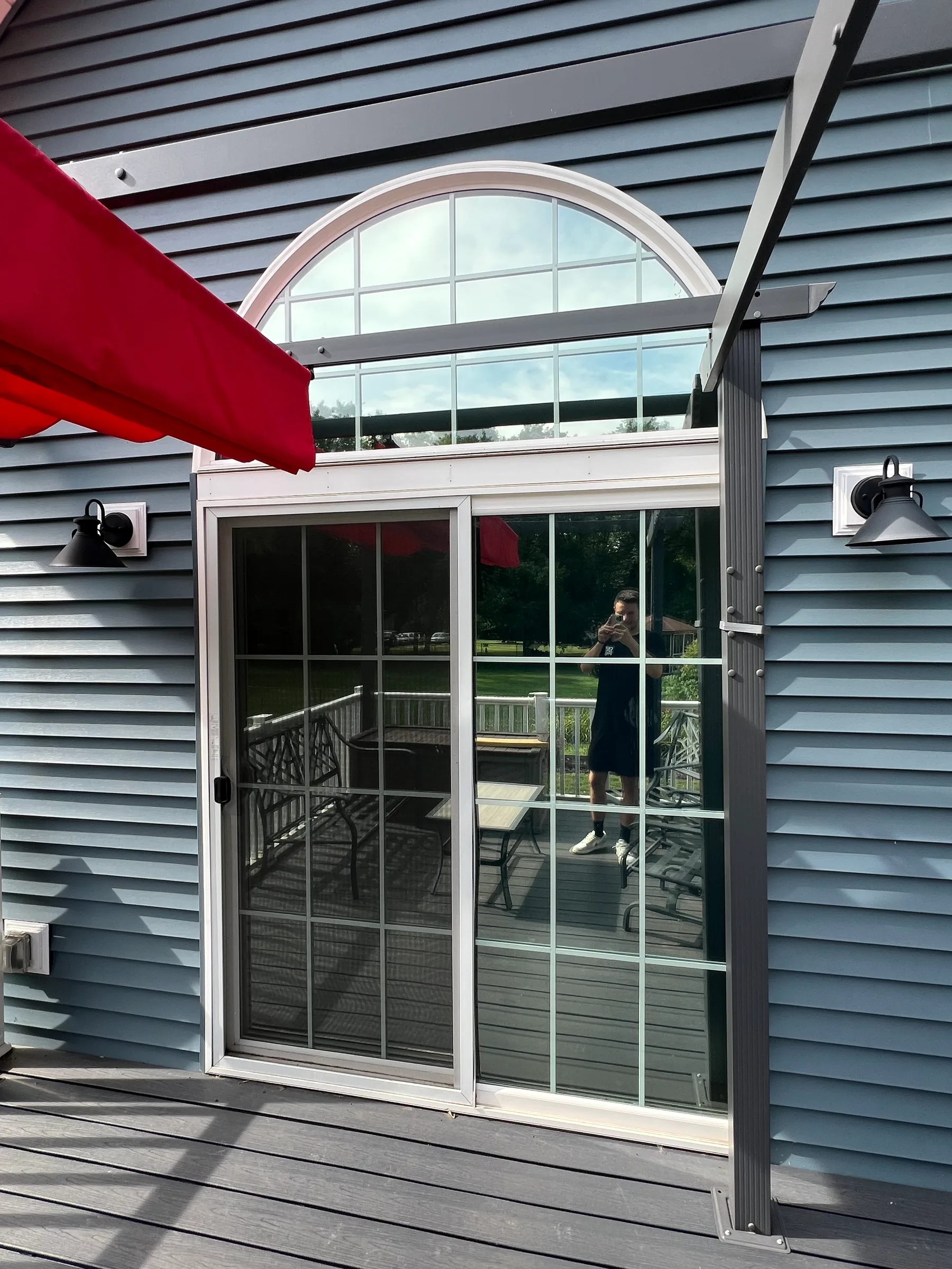 Large glass patio doors and transom windows with dark residential window tint applied, reducing glare on a deck.