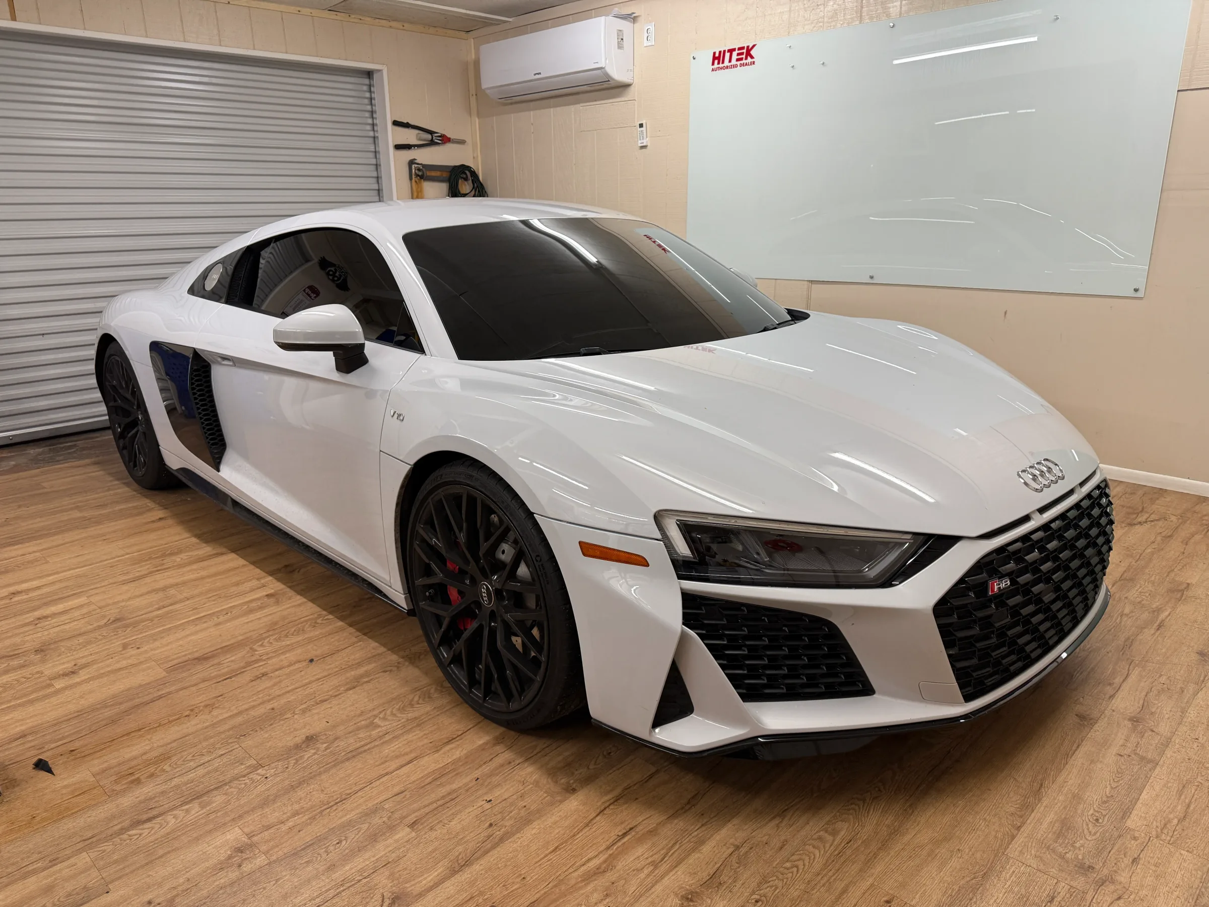 White Audi R8 with dark window tint applied, displayed indoors in a professional automotive shop in Cave Creek.
