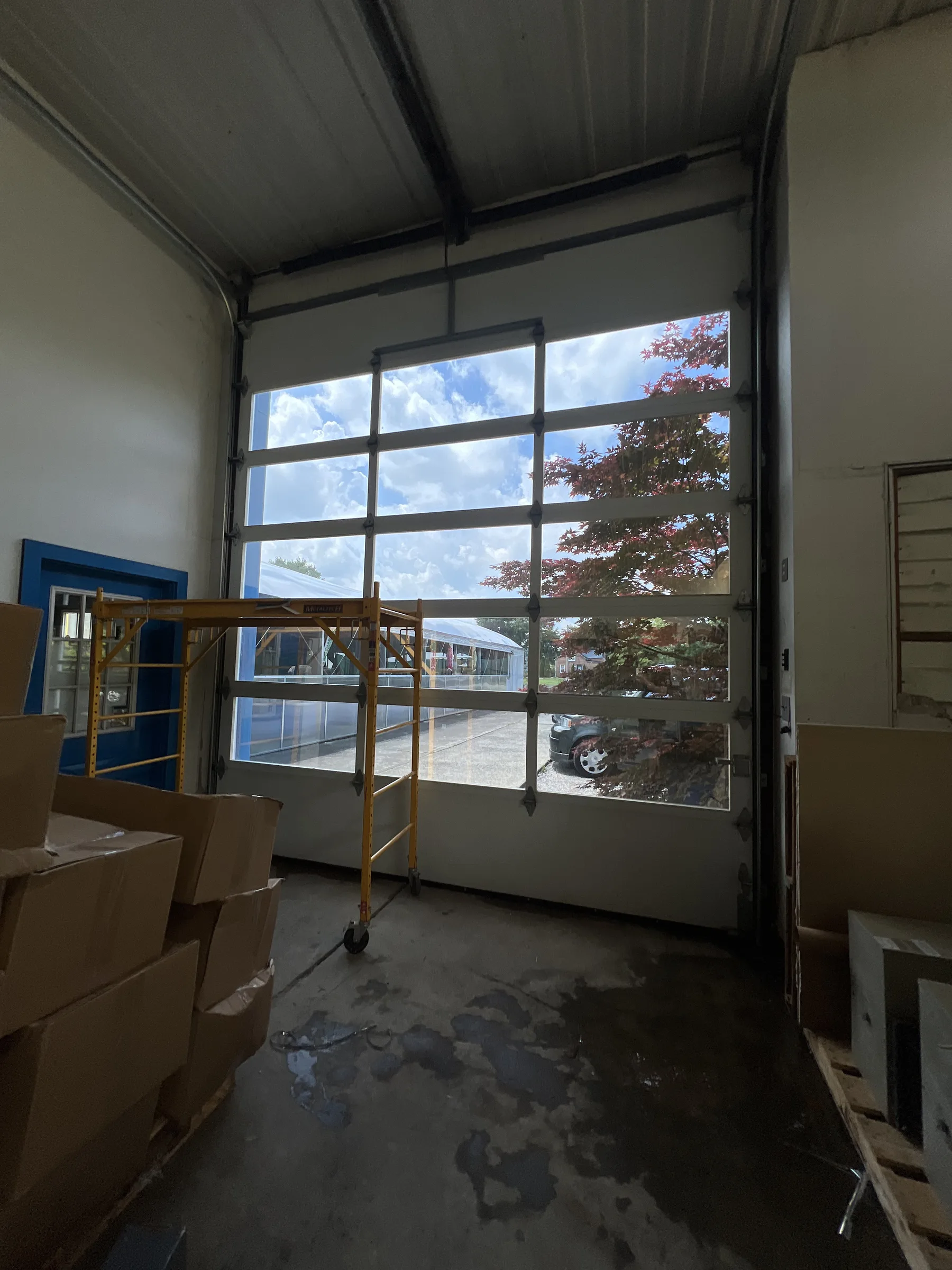Interior view of a shop workspace with a large commercial storefront window displaying window tint film application.