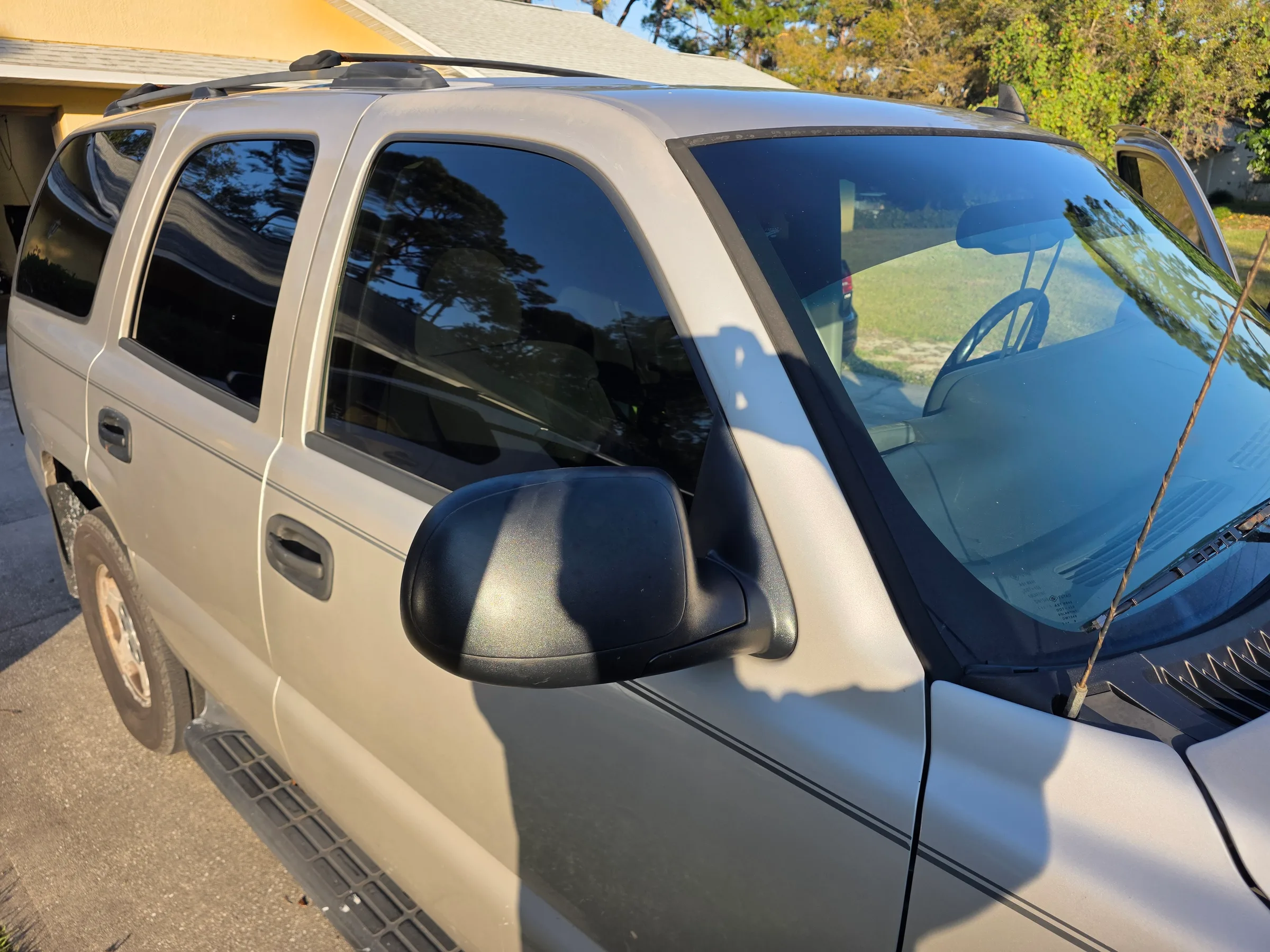 White SUV with dark window tint applied to the side and rear windows, parked in a driveway.
