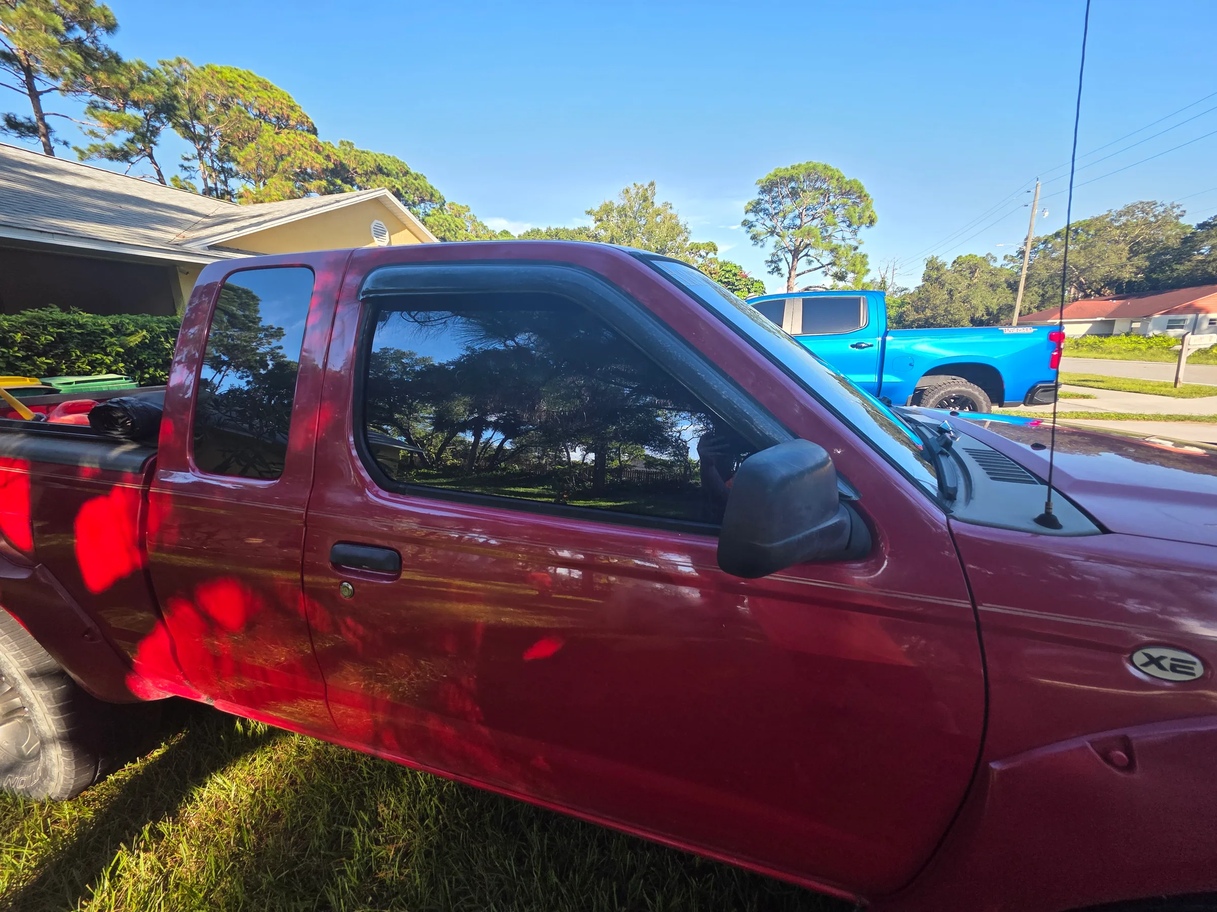 A maroon pickup truck with dark window tint applied to the cab windows, displayed in a sunny outdoor lot.