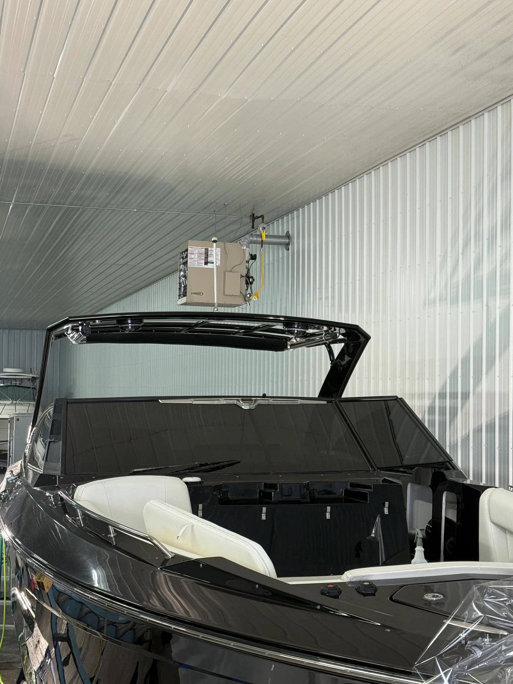 A black pickup truck with its tonneau cover open, revealing a white leather interior during installation in a professional workshop.