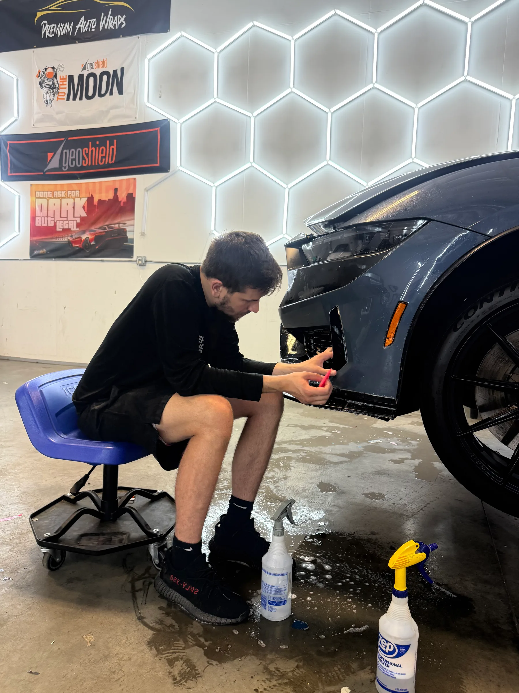 A technician applies protective film to a vehicle headlight during installation at Premium Auto Wraps in Berea, OH.