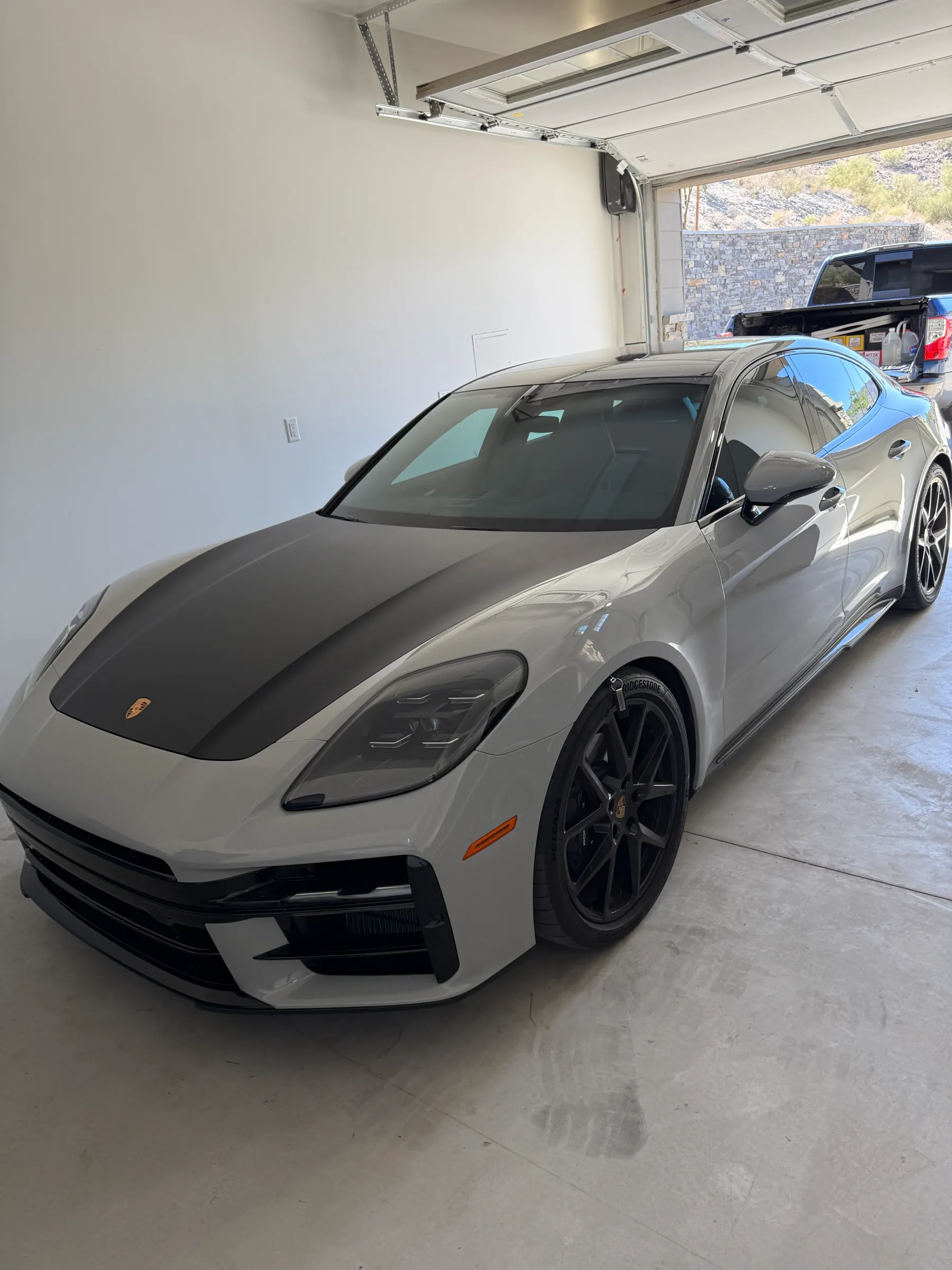 White Porsche Panamera with paint protection film applied to the hood, displayed in a professional detailing garage.