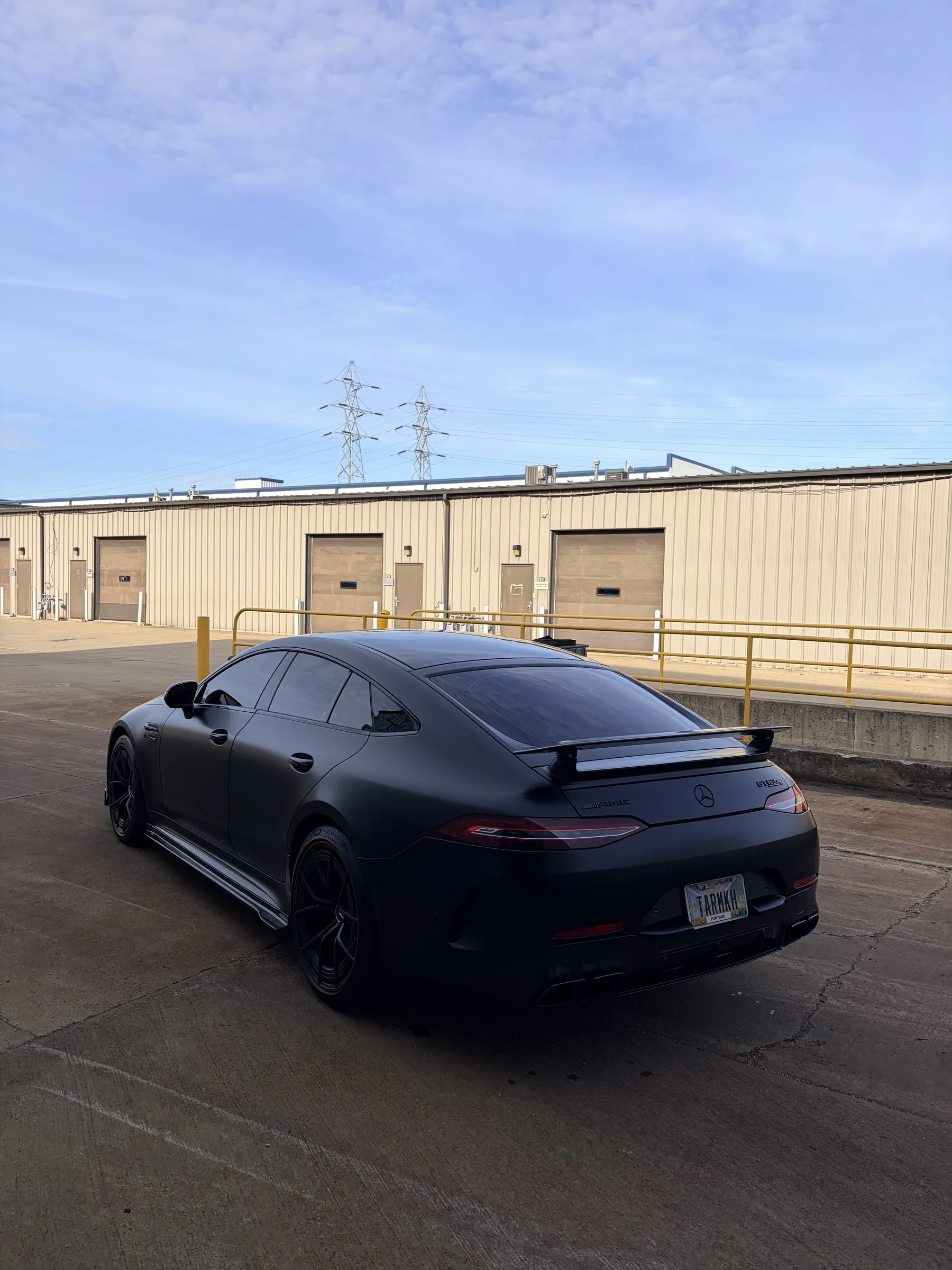 A matte black Mercedes-AMG GT sedan parked in front of an industrial warehouse building in Berea, Ohio.