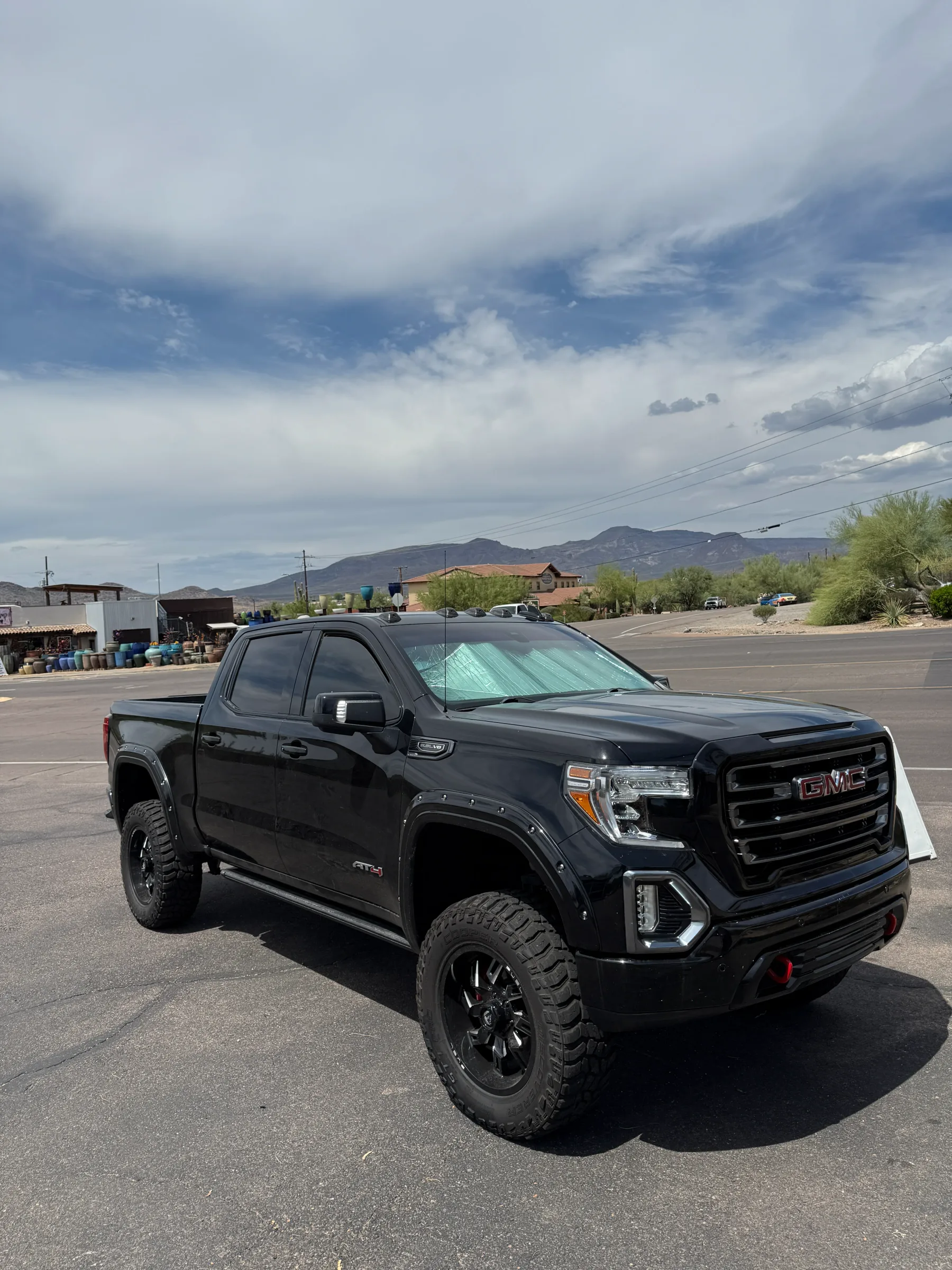 Black GMC Sierra pickup truck with dark window tint installed, parked in a lot with desert mountains and Arizona landscape in the background.