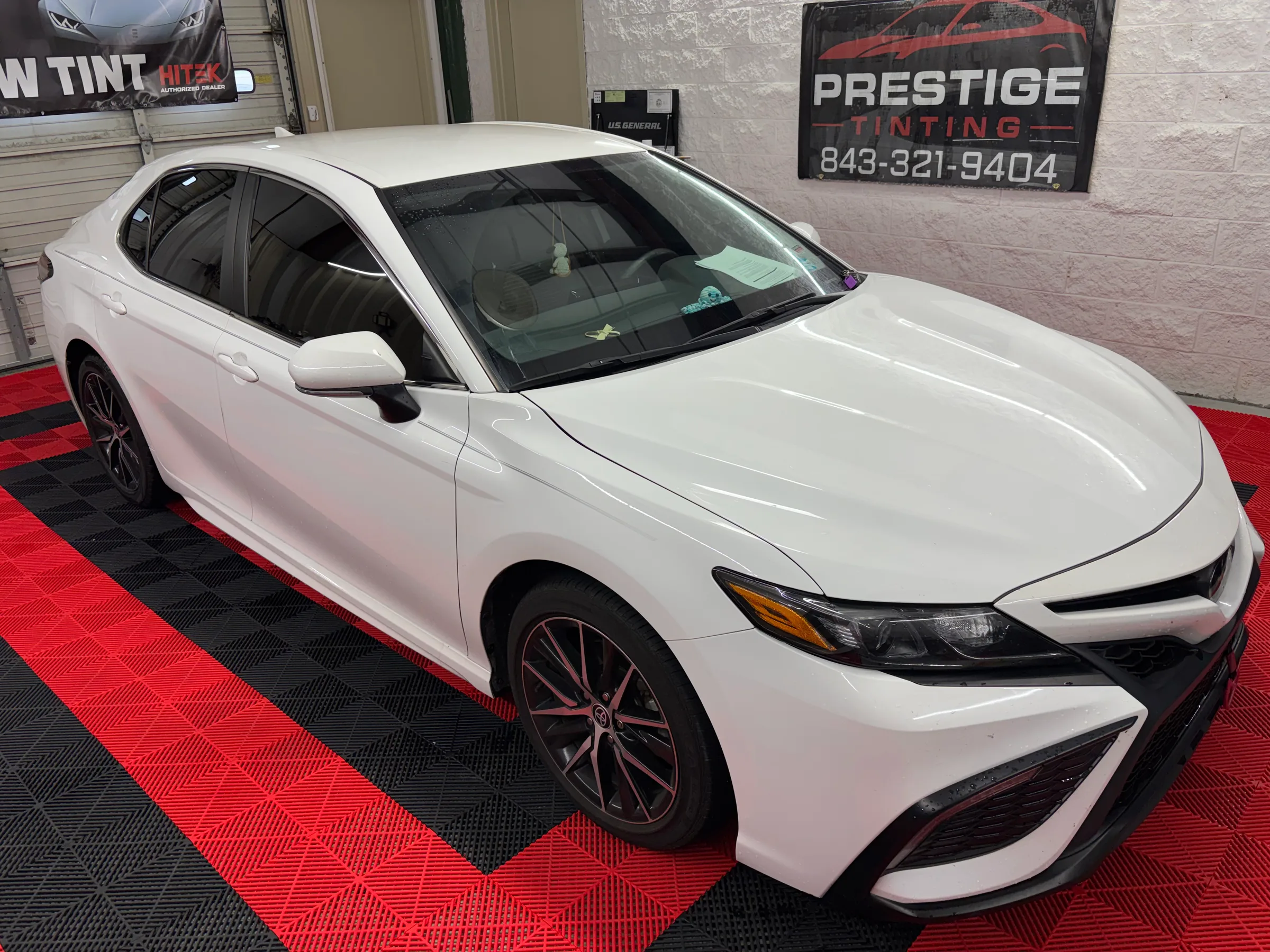 A white Toyota Camry with dark window tinting displayed in a Prestige Tinting shop in Conway, SC.