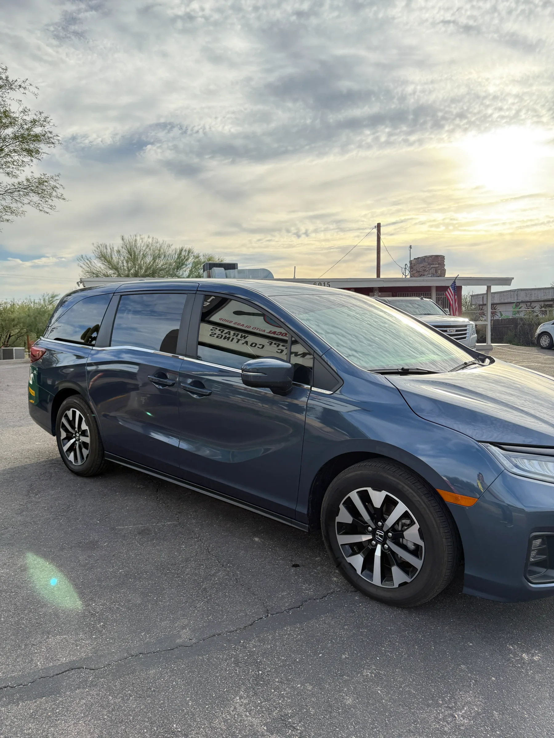A blue Honda Odyssey minivan with dark window tint applied, parked at a desert shop in Cave Creek, Arizona.