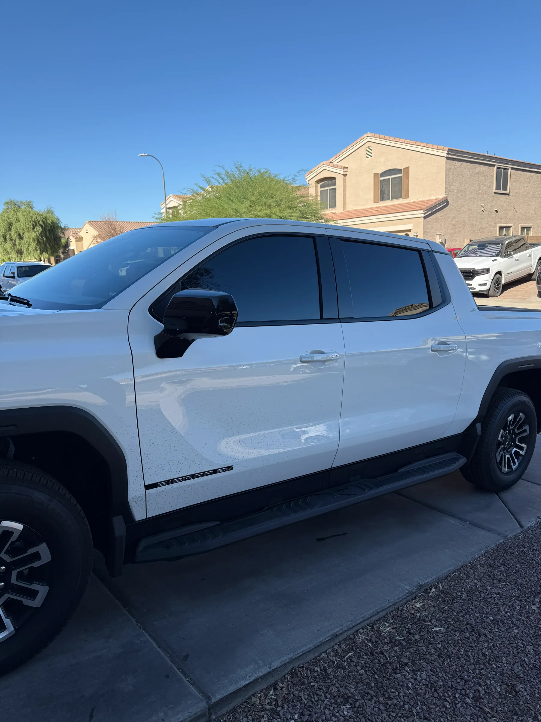 White GMC Sierra pickup truck with dark window tint applied to the rear and side windows, parked in a residential driveway in Cave Creek, Arizona.