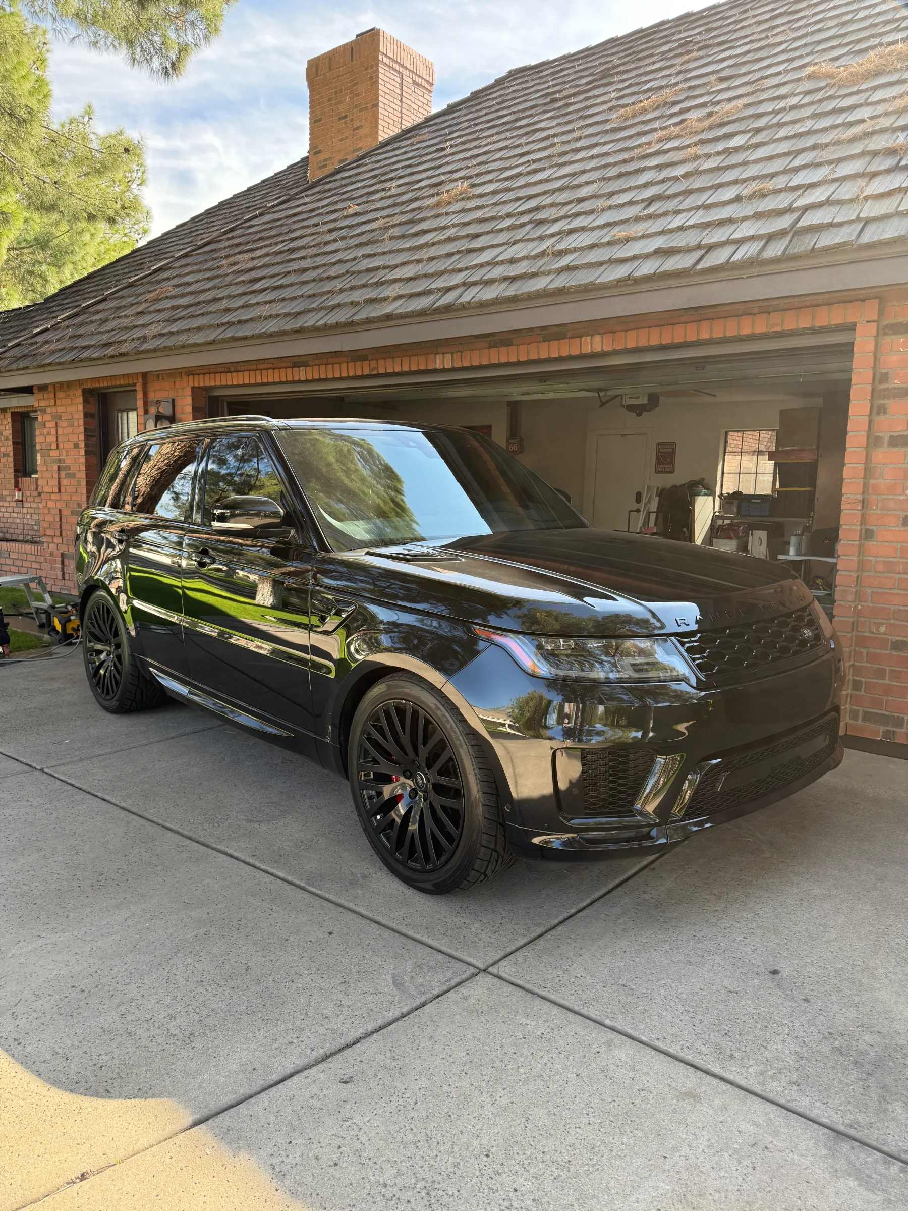 A gleaming black Range Rover with dark window tint parked in a residential driveway in Cave Creek, Arizona.