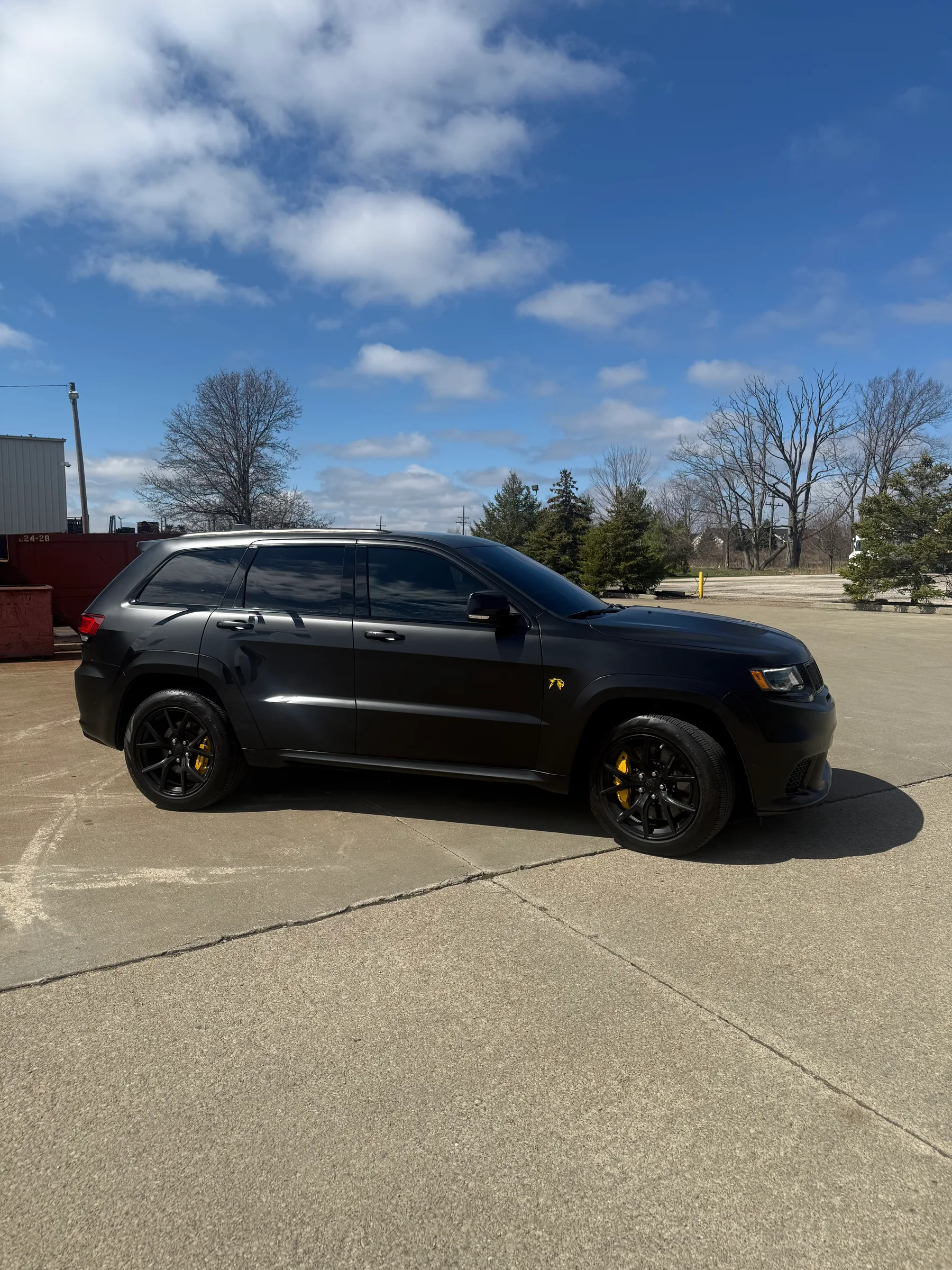 Black Jeep Grand Cherokee with dark window tint and yellow brake calipers parked in a lot in Berea, Ohio.